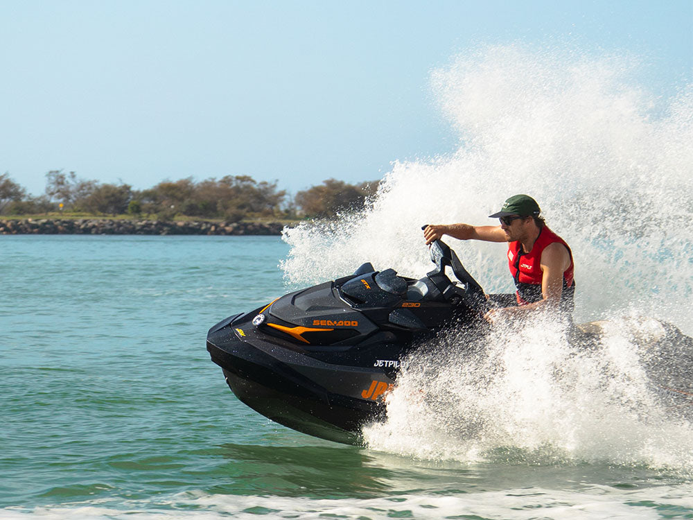 Licensed rider in a red Jetpilot PFD carving a Sea-Doo jet ski through spray on an Aussie waterway
