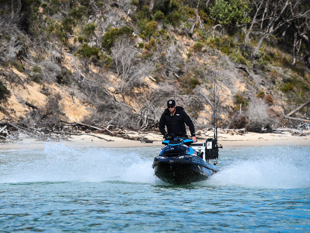 Solo rider in a black Jetpilot tour coat heading out on a Sea-Doo across a sheltered bay