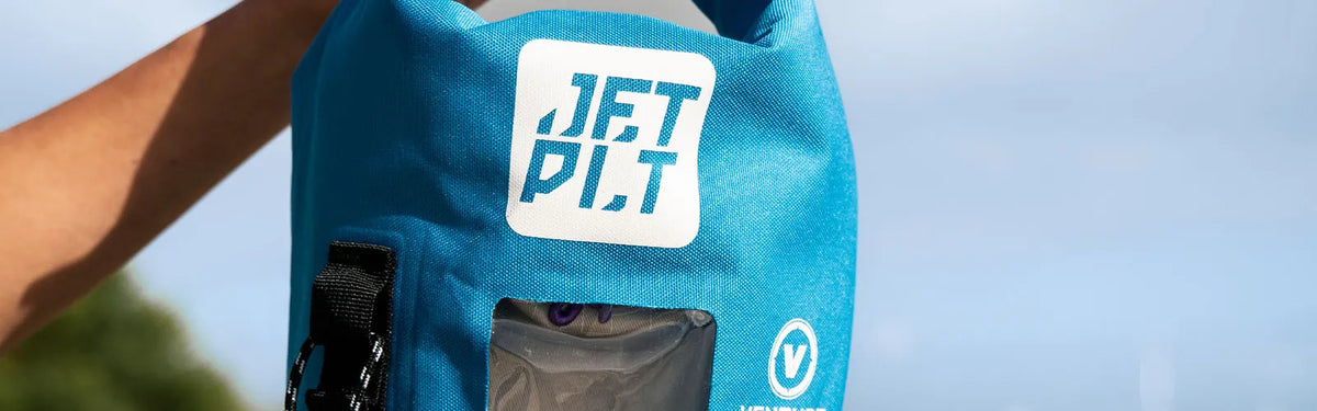 Close-up of a blue Jetpilot Venture waterproof dry bag held up against a clear Aussie sky
