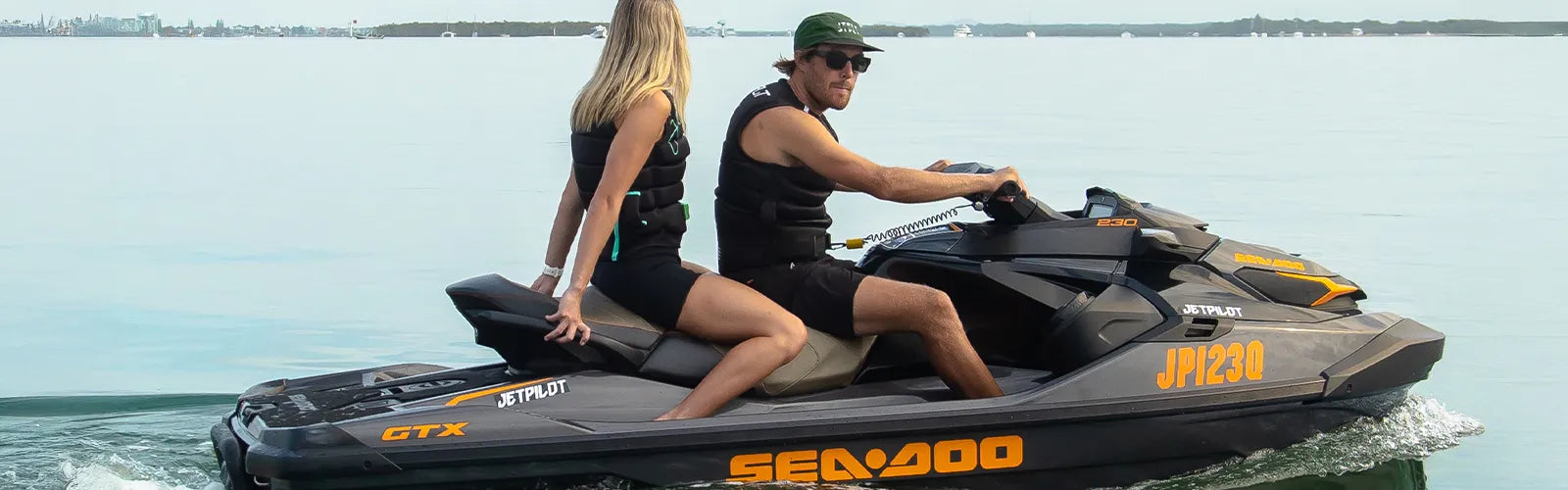 Couple in Jetpilot life jackets riding a Sea-Doo jet ski across the Gold Coast Broadwater