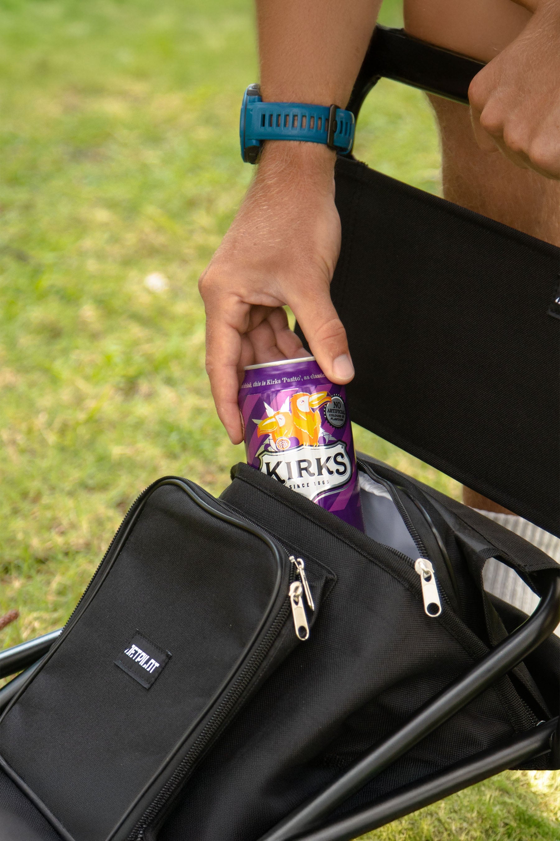Person sitting outdoors with a Jetpilot Back Rest Chilled Seat Bag - Black and a purple can of Kirks Passito — image 2
