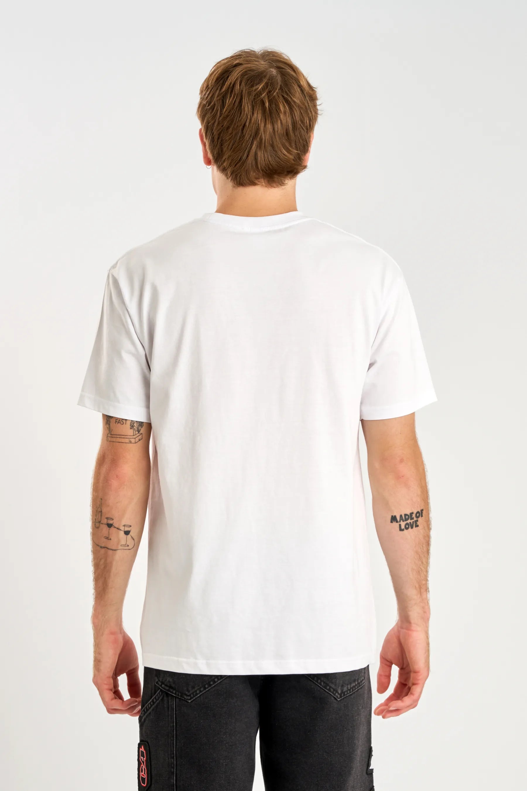 Back view of person wearing a plain white t-shirt on a light gray background