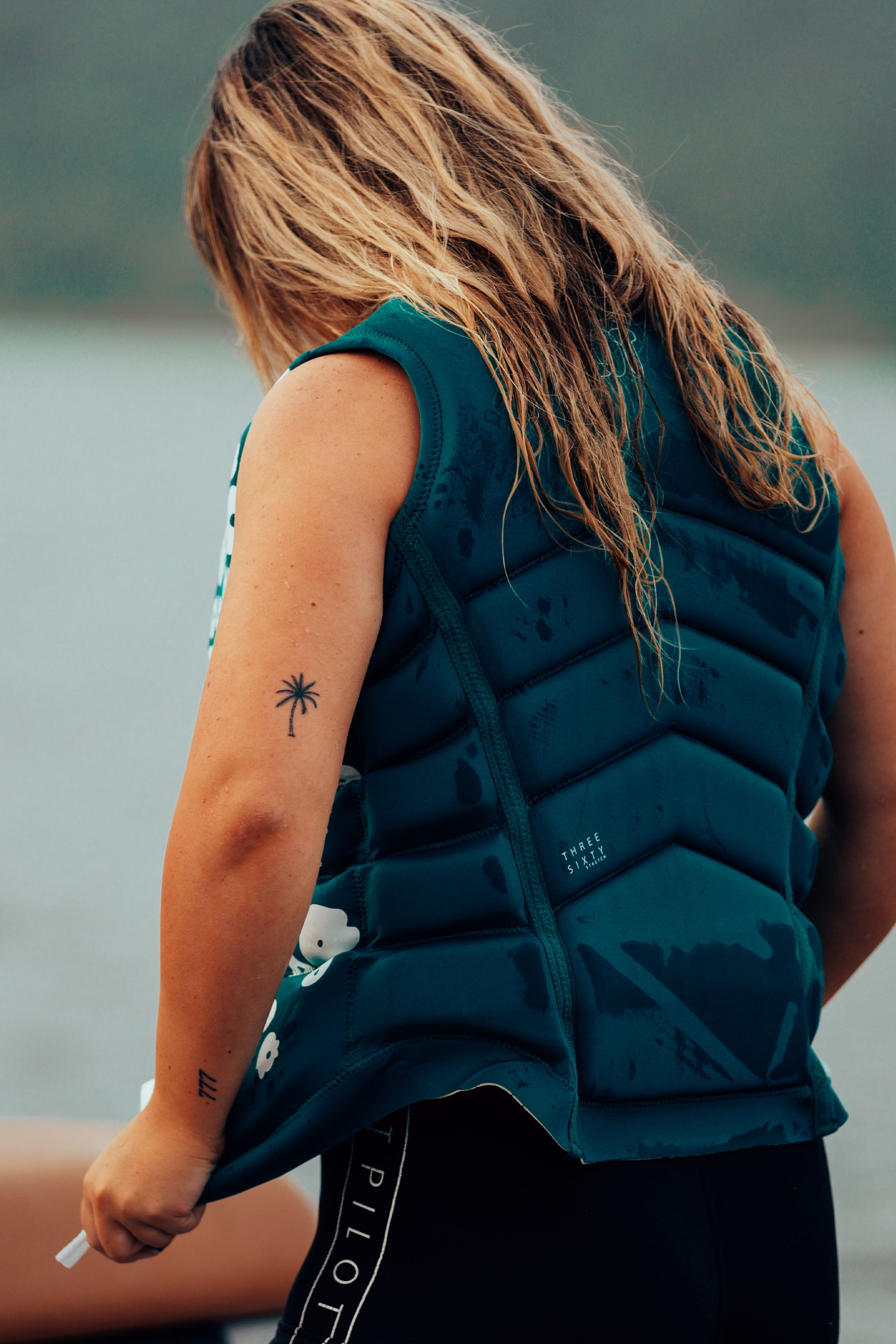 Person wearing a Jetpilot X1 Ladies Life Jacket - Isla - Green by a body of water