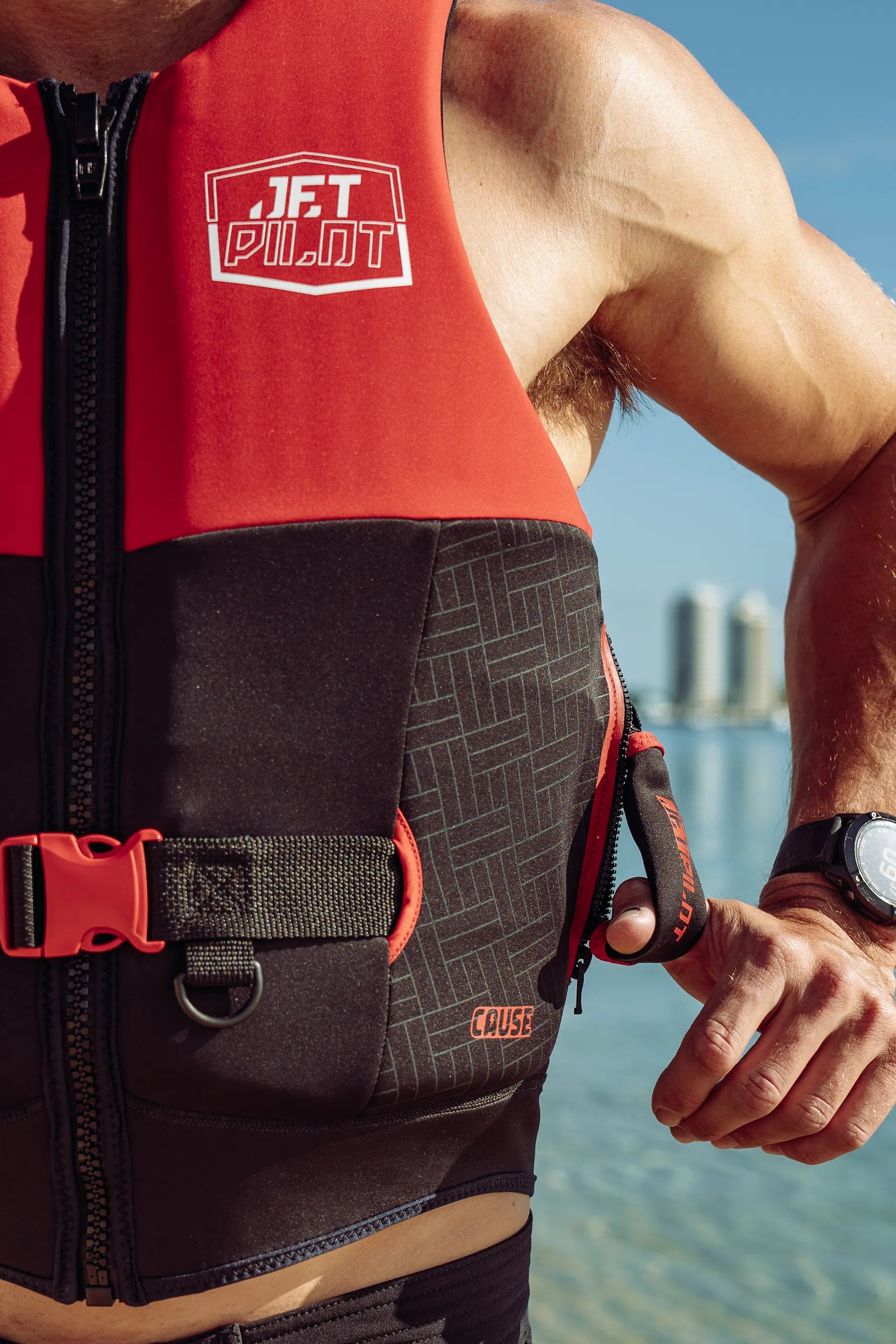 Person wearing a red and black life jacket with a city skyline in the background