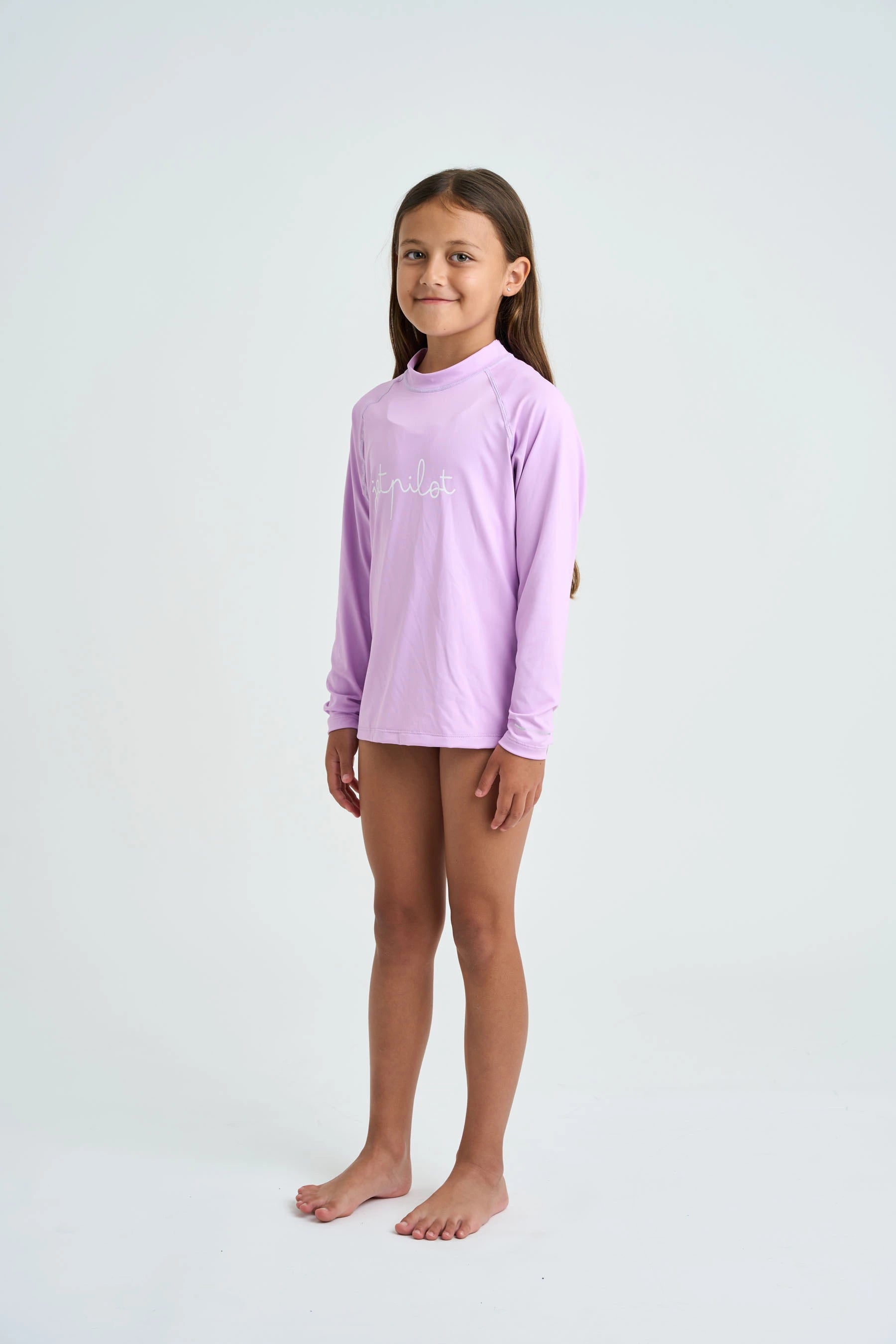 Young girl wearing a light purple long-sleeve shirt on a white background