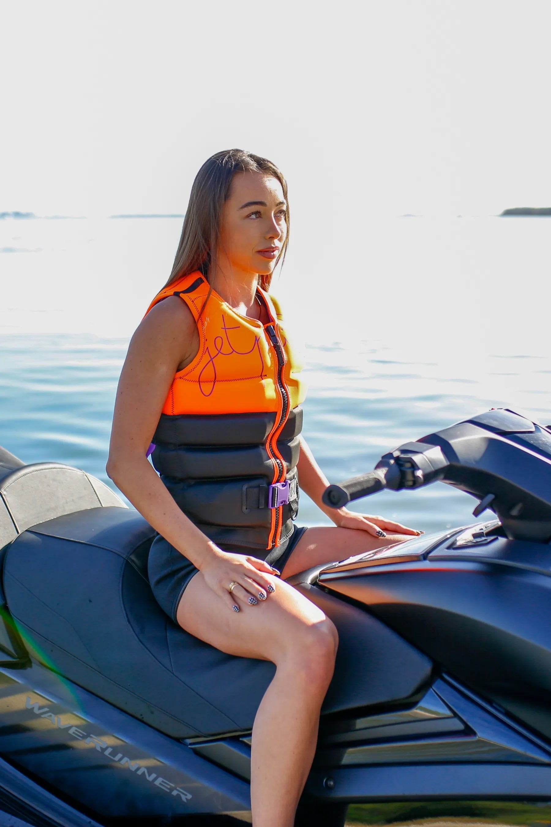 Woman in an orange life jacket sitting on a jet ski in the water. — view 4 (3)