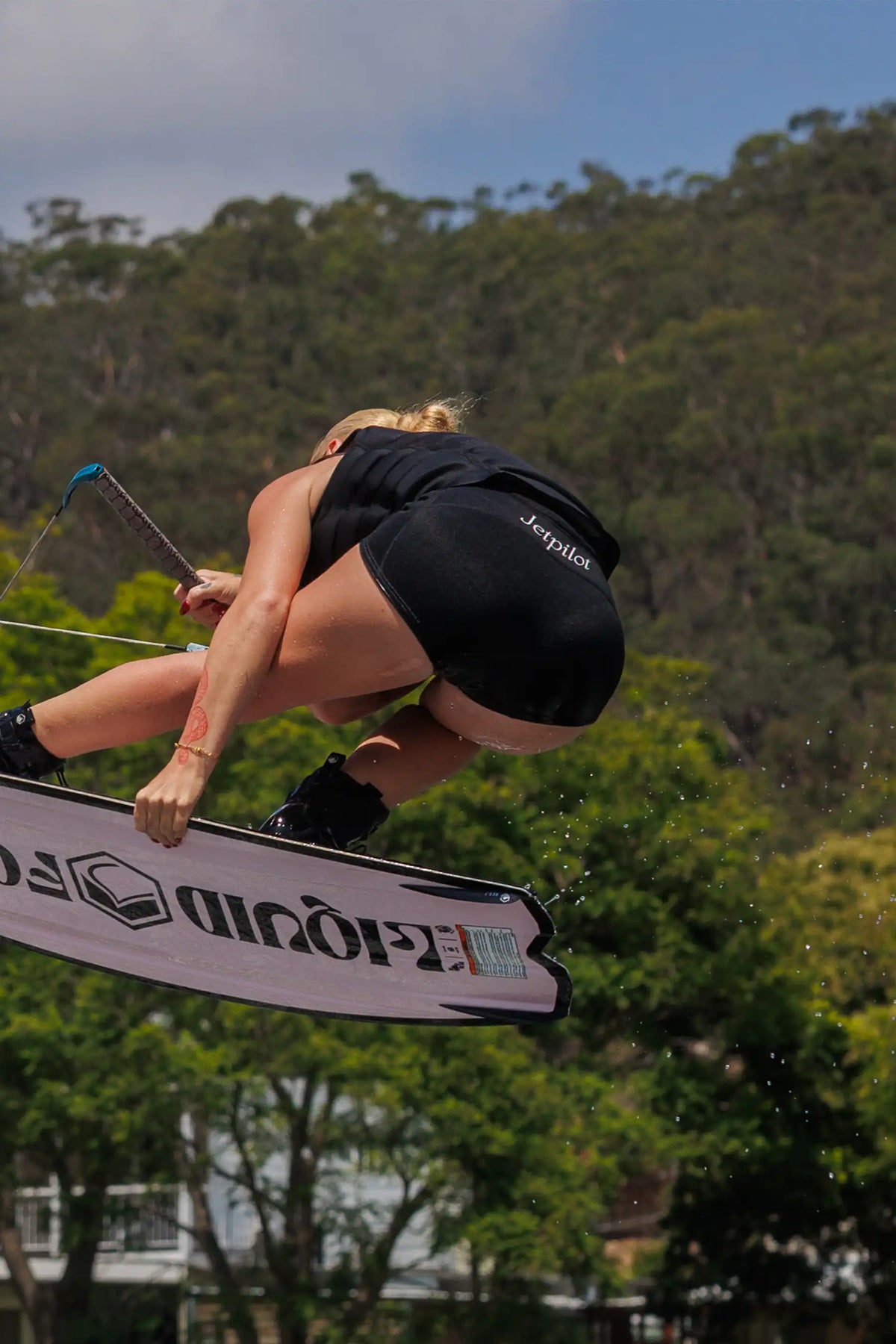 Rider upside down mid-air on a wakeboard in the Black Zahra 2.5" shorts, with the Jetpilot script on the back