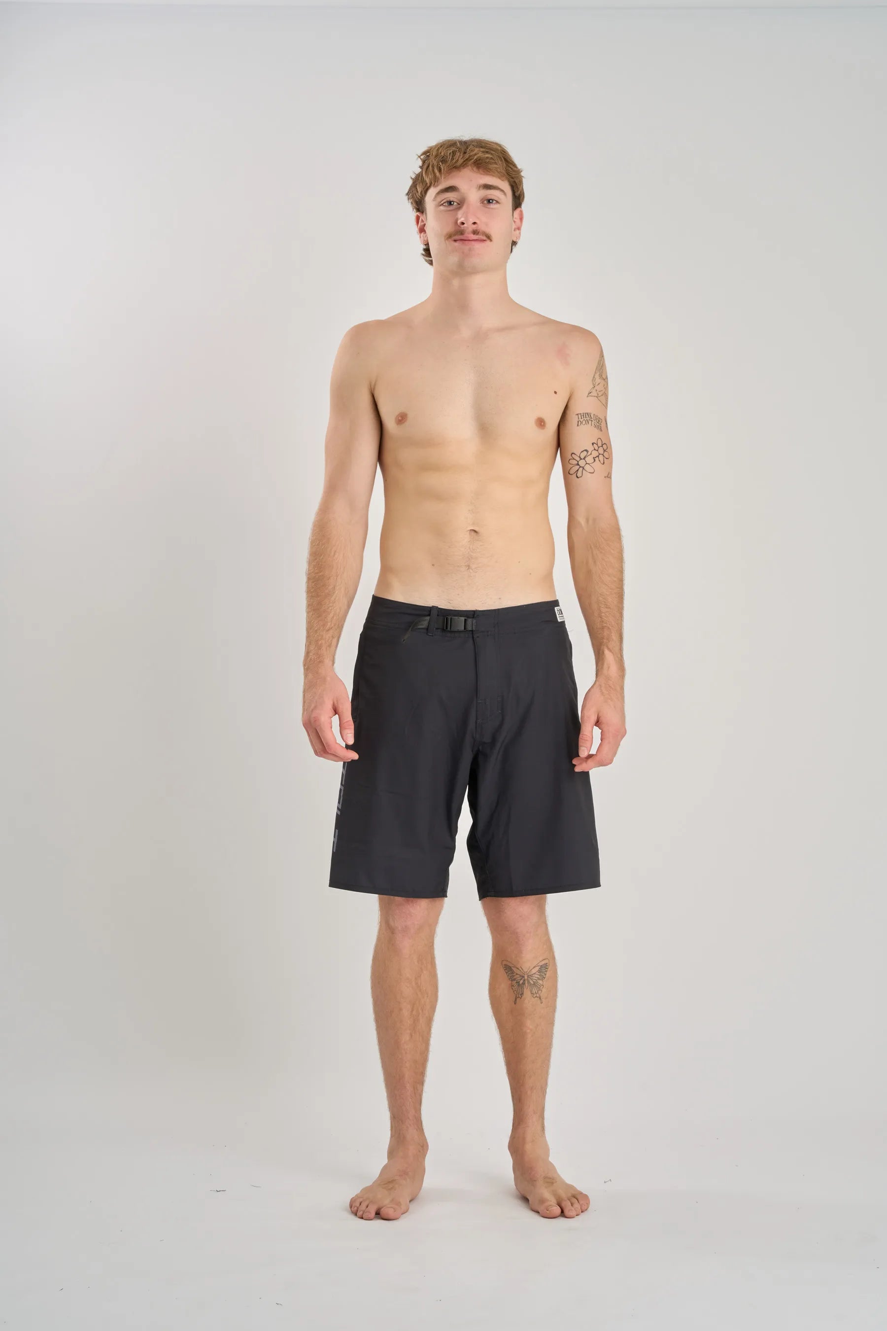 Man wearing black Jetpilot board shorts on a white background