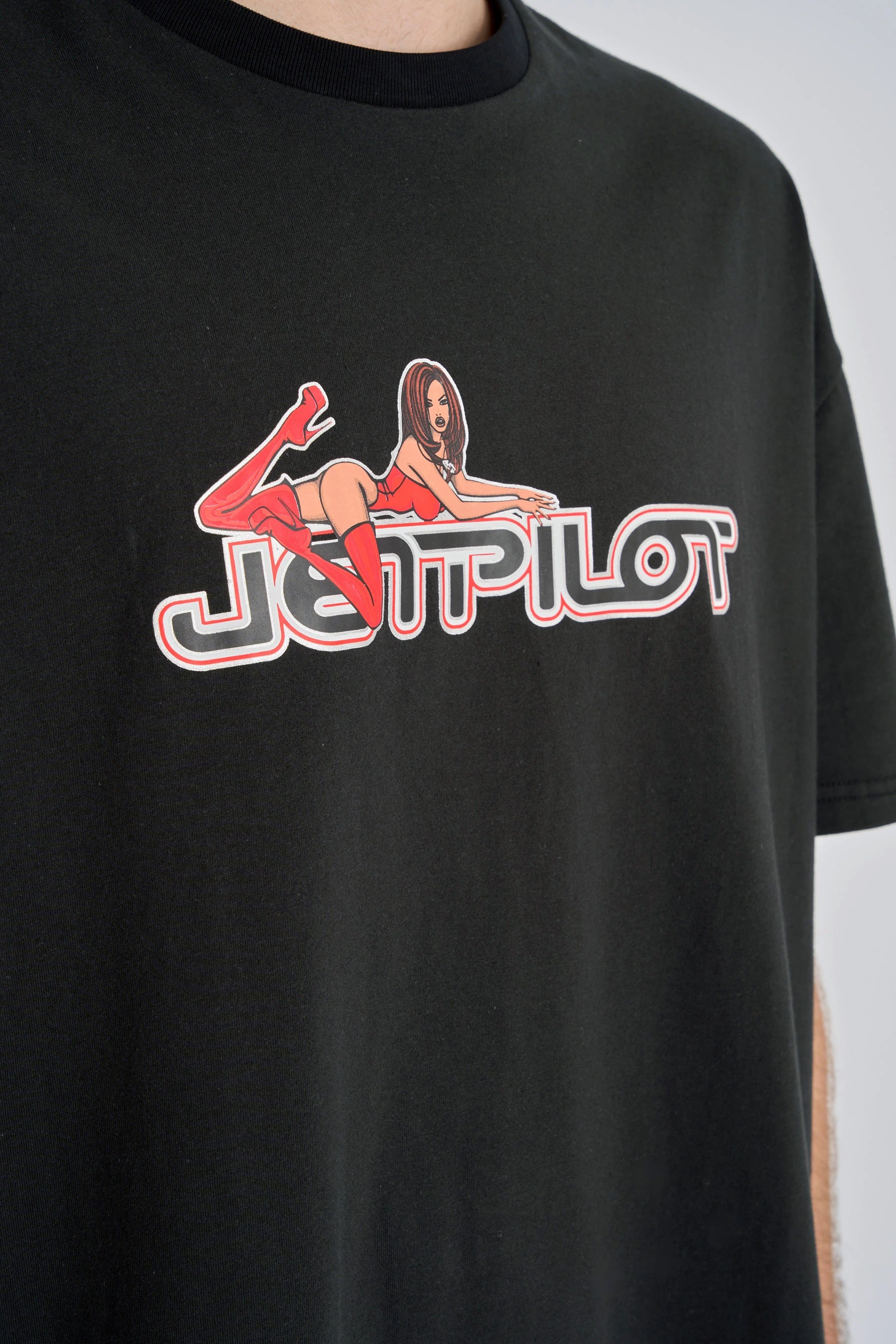 Black t-shirt with a graphic design featuring a woman lying on the logo 'JETPILOT' on a plain background