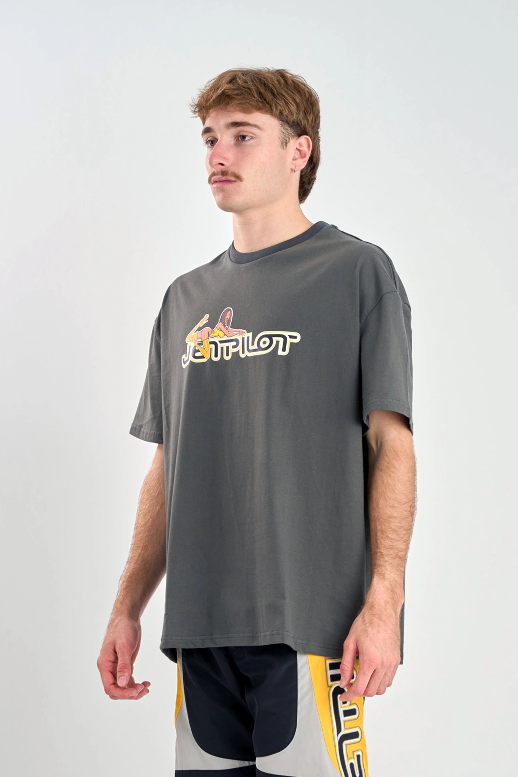 Person wearing a Jetpilot Moto Heavy Tee - Charcoal with a logo on a white background