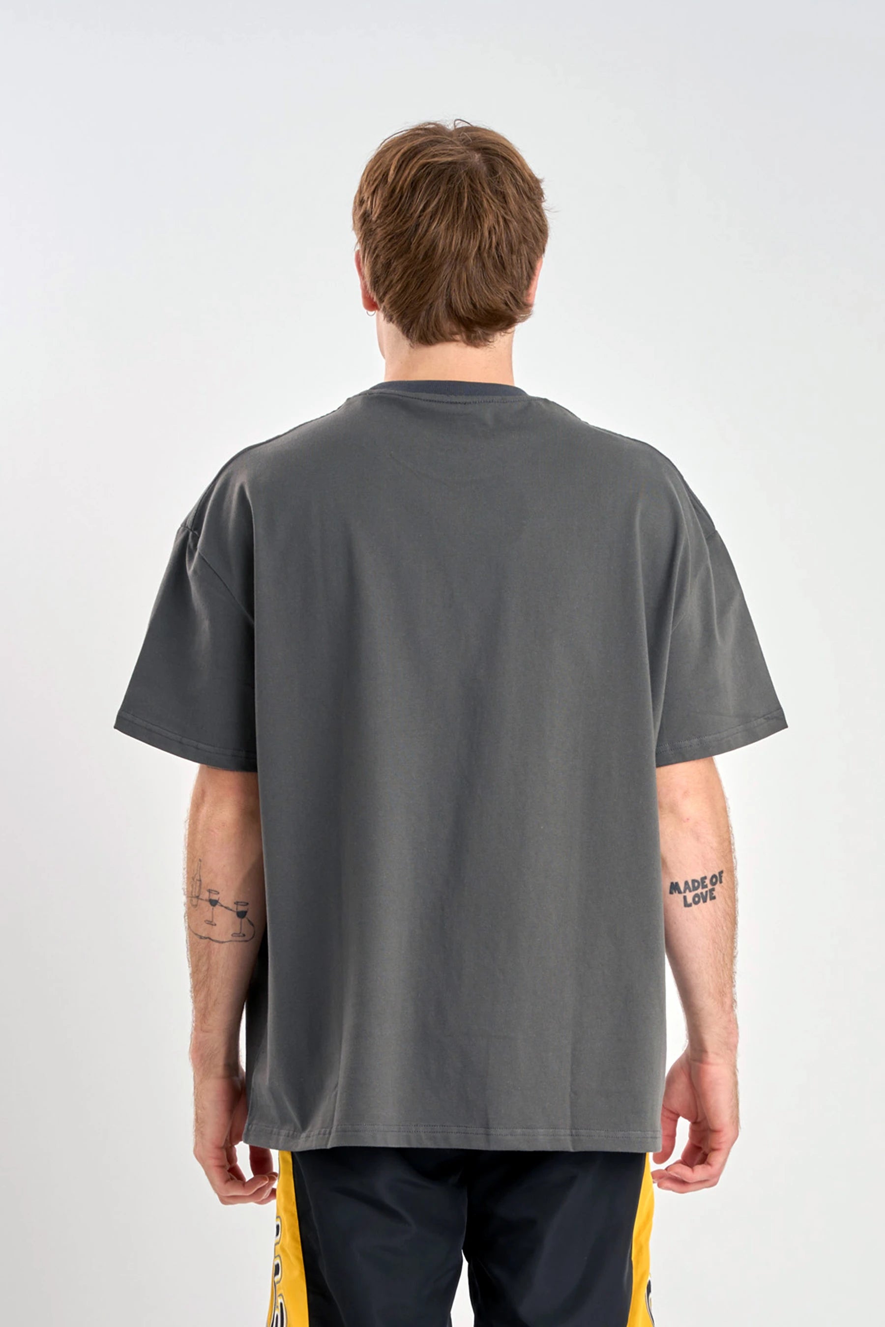 Person wearing a Jetpilot Moto Heavy Tee - Charcoal, back of shirt, plain charcoal with a plain background