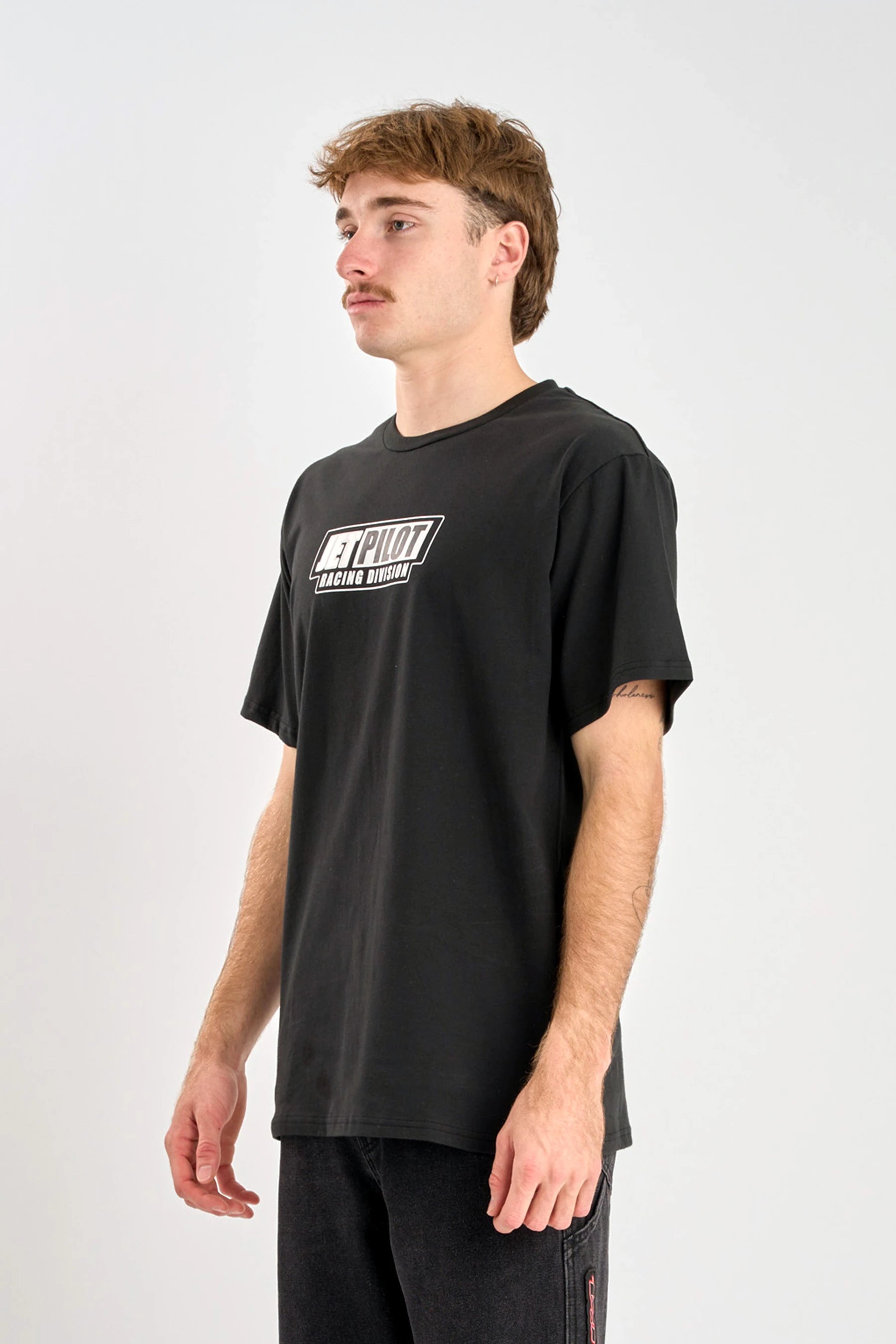 Person wearing a Jetpilot Pulse Streamliner Tee - Black t-shirt with a logo on a white background — image 2