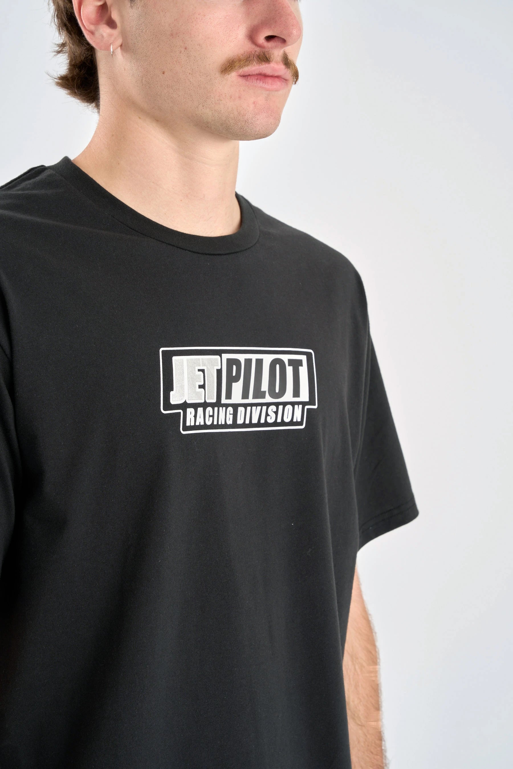 Person wearing a black t-shirt with 'Jetpilot Racing Division' logo on a white background — image 2