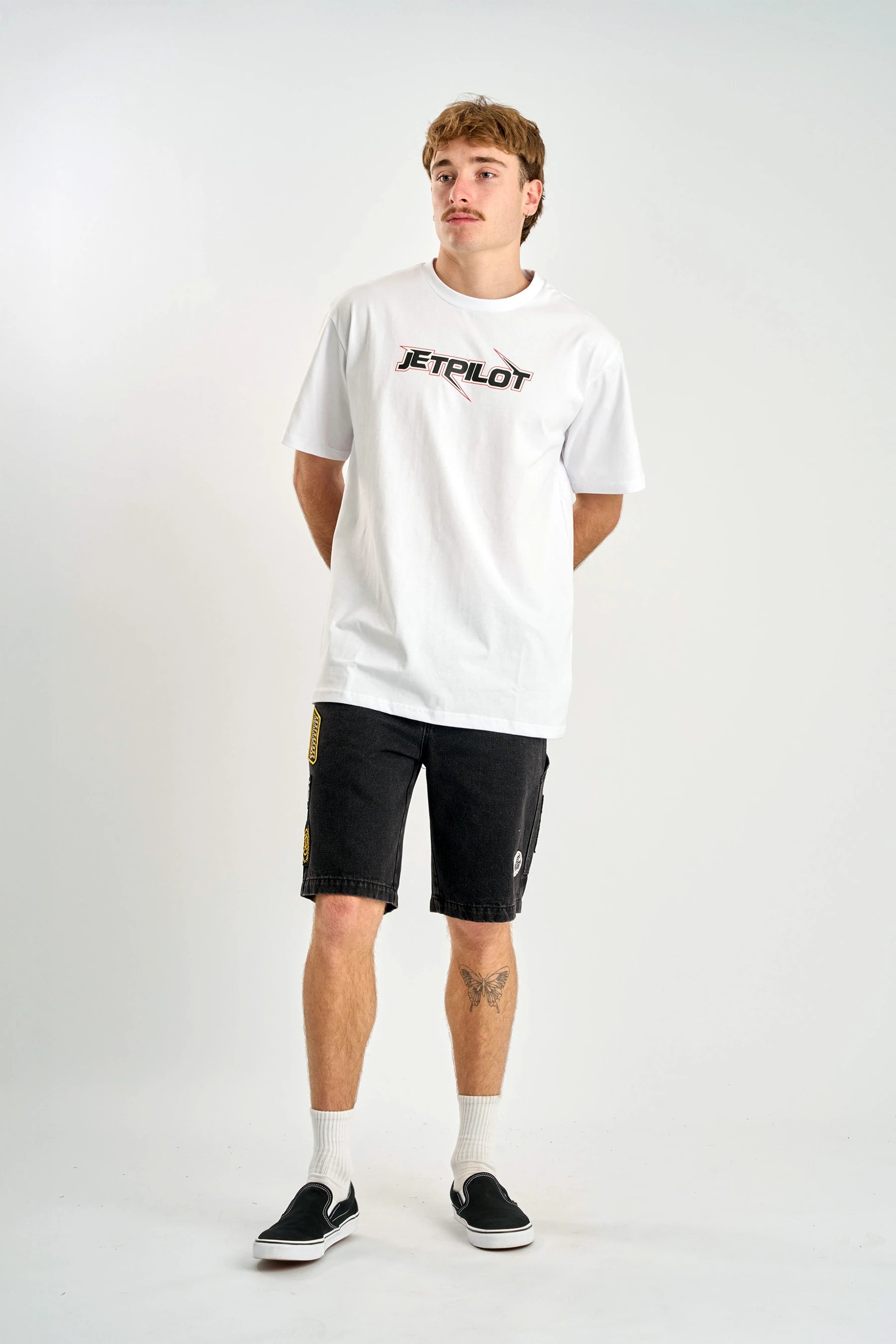 Person wearing a white t-shirt with 'Jetpilot' logo and black shorts on a white background — image 2