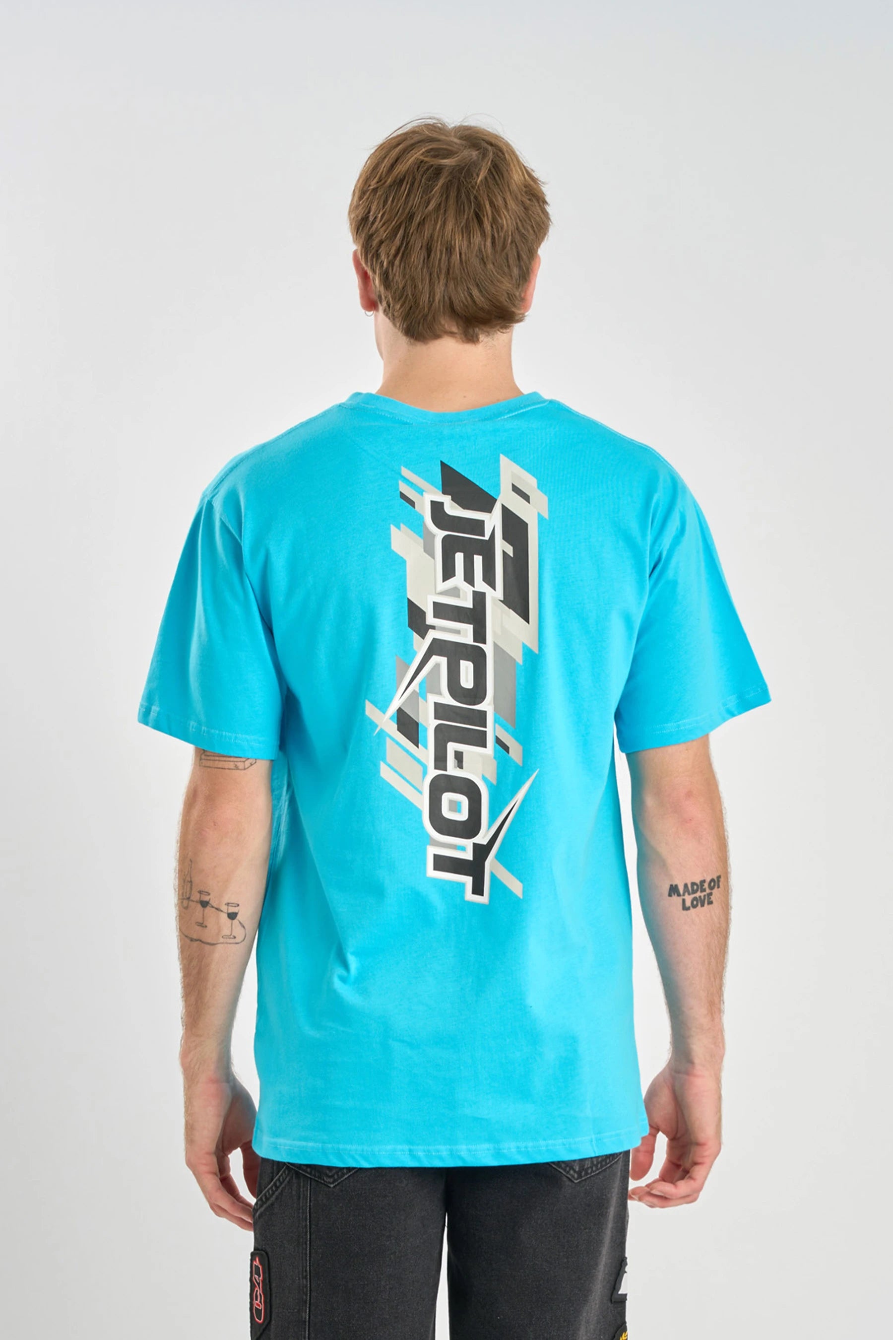 Person wearing a Jetpilot Raptor Tee - Blue t-shirt with a logo on the back against a white background — image 2