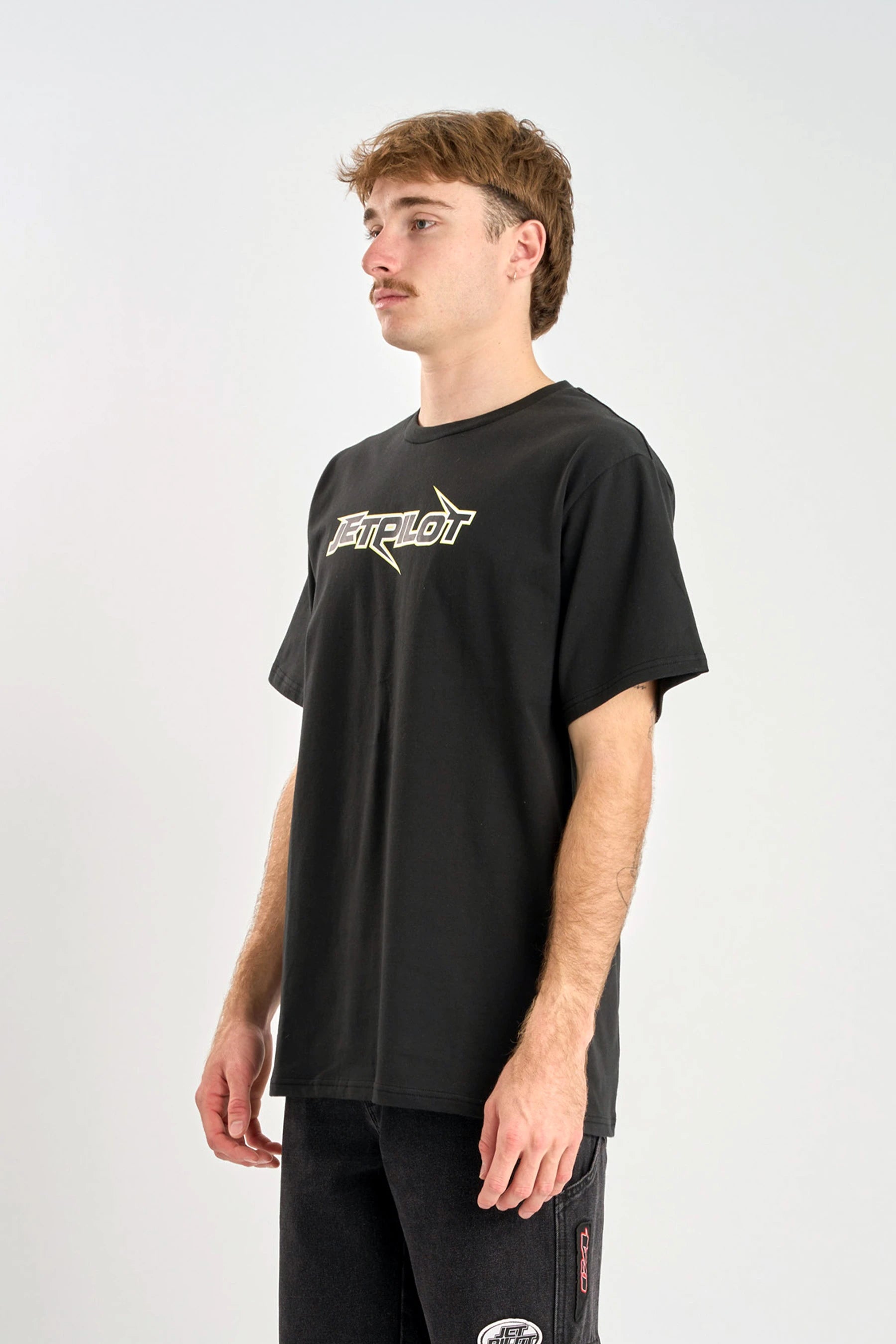 Person wearing a Jetpilot Raptor Tee - Black t-shirt with a logo on a white background — image 2