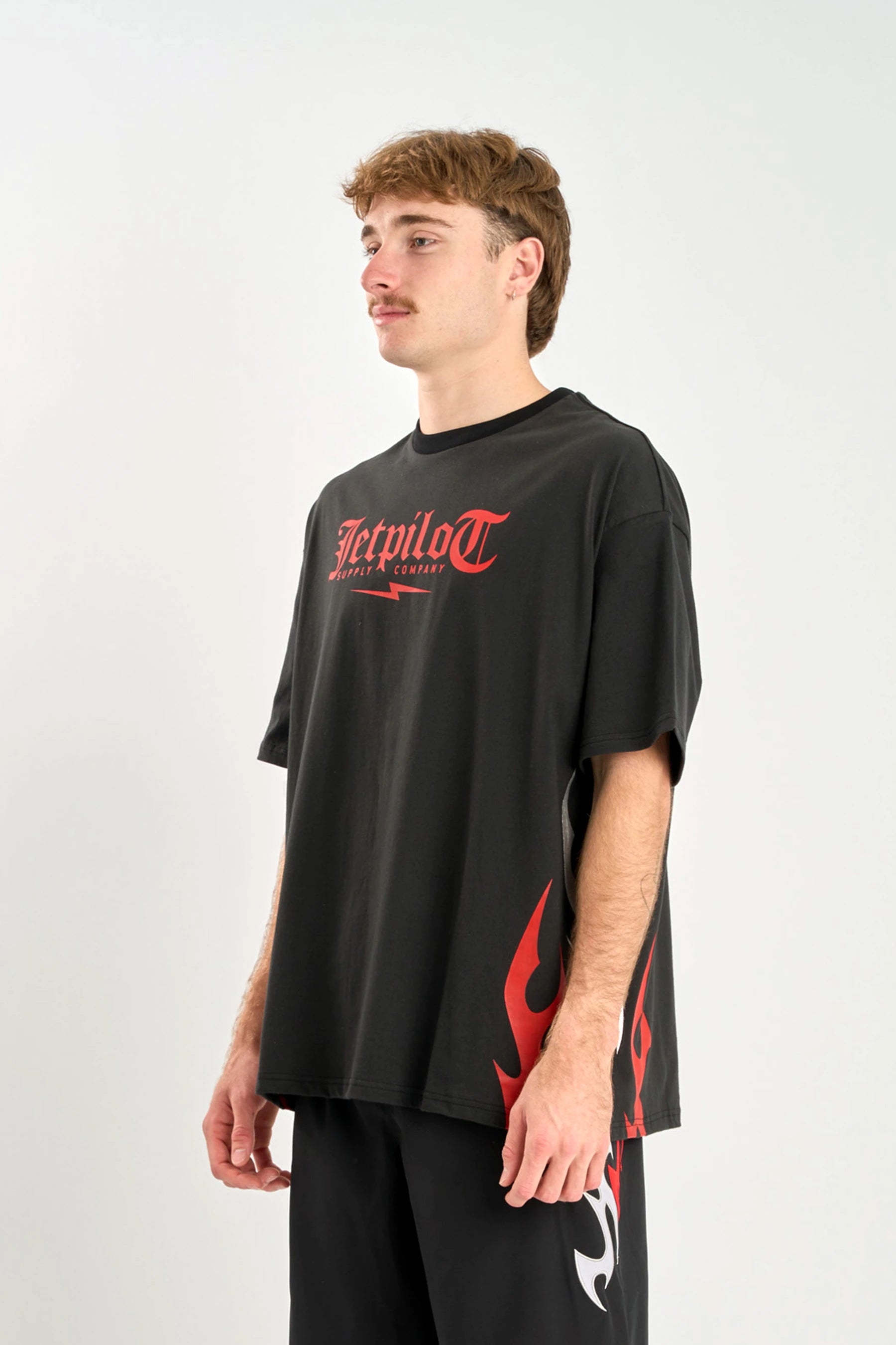 Person wearing a black t-shirt with red graphics and text on a white background — image 2