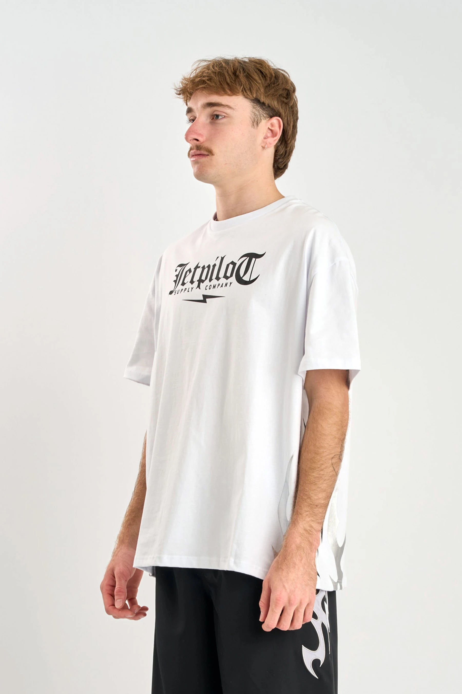 Person wearing a white t-shirt with a logo on a plain background — image 6