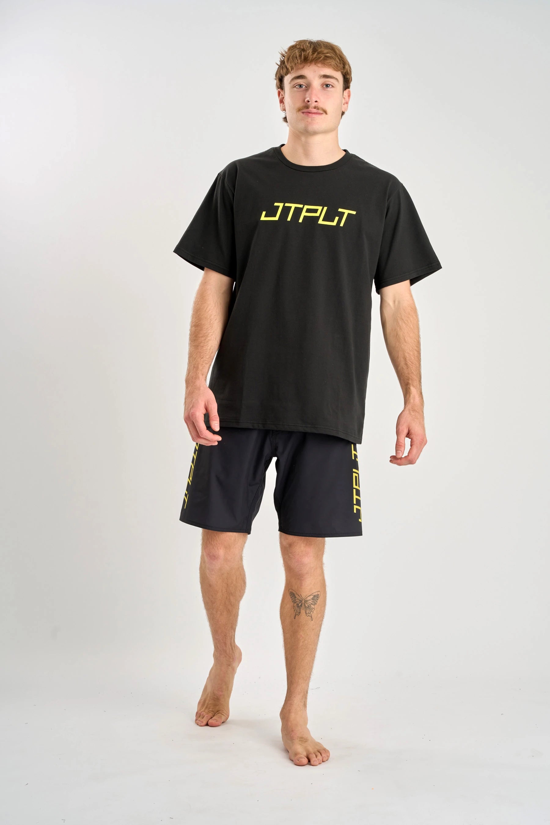 Man wearing a black t-shirt and shorts with 'JPTLT' branding on a white background — image 2