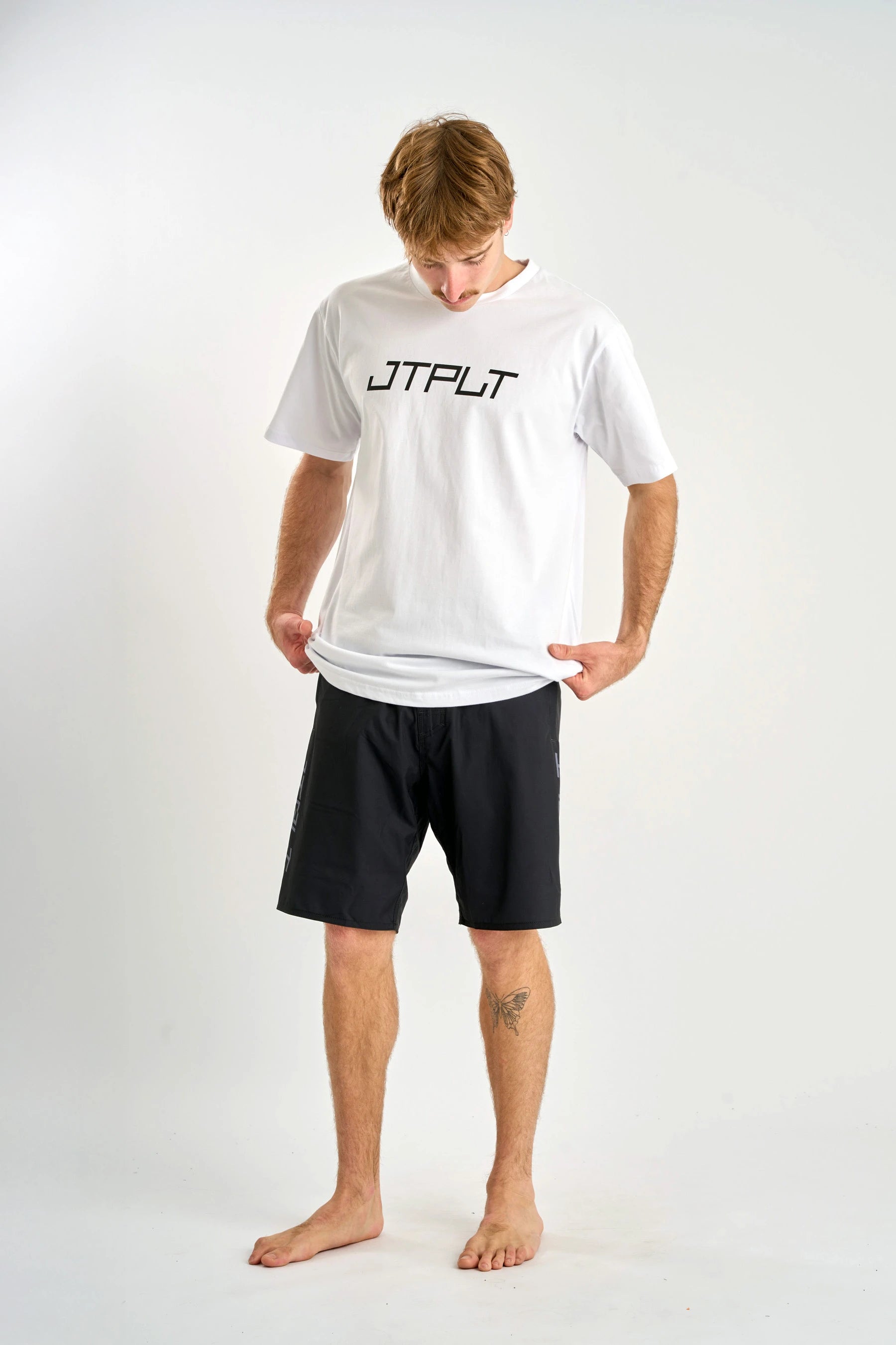 Man wearing a white t-shirt with 'JTPLT' logo and black shorts on a white background — image 2
