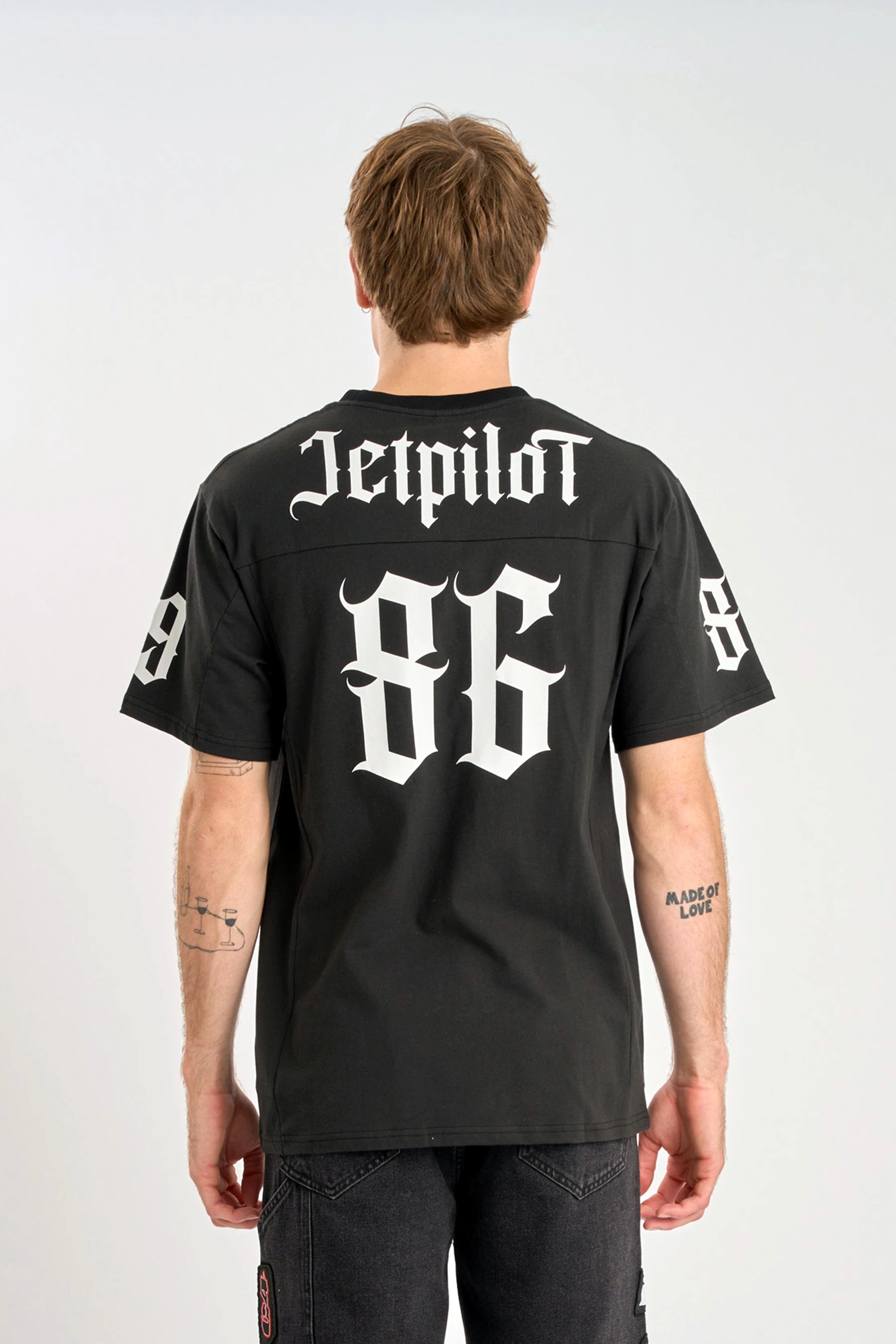 Person wearing a Jetpilot Battle Heavy Tee - Black with 'Jetpilot' and '86' printed on the back, standing against a white background.