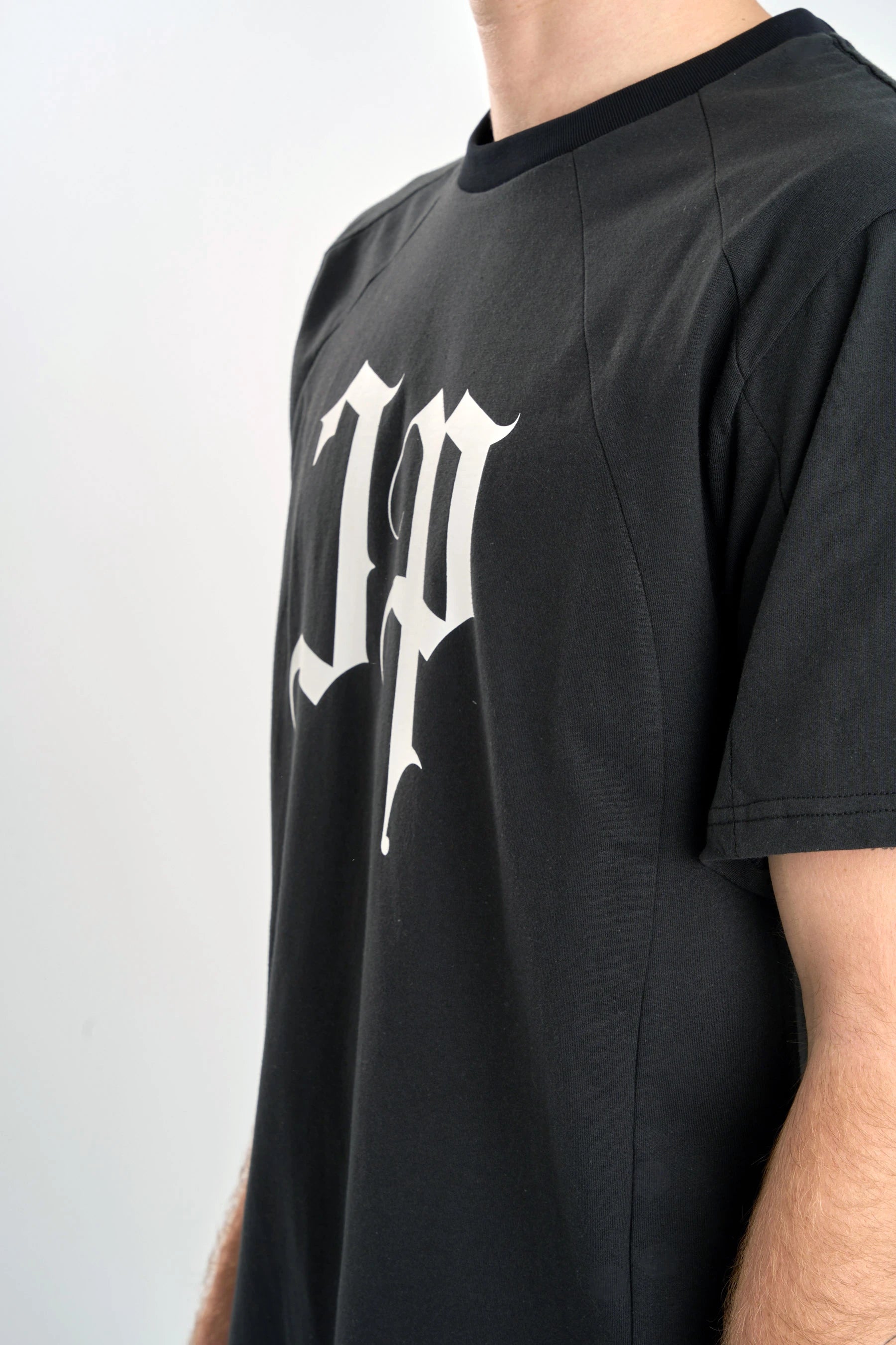 Black t-shirt with a white "JP" logo on a plain background