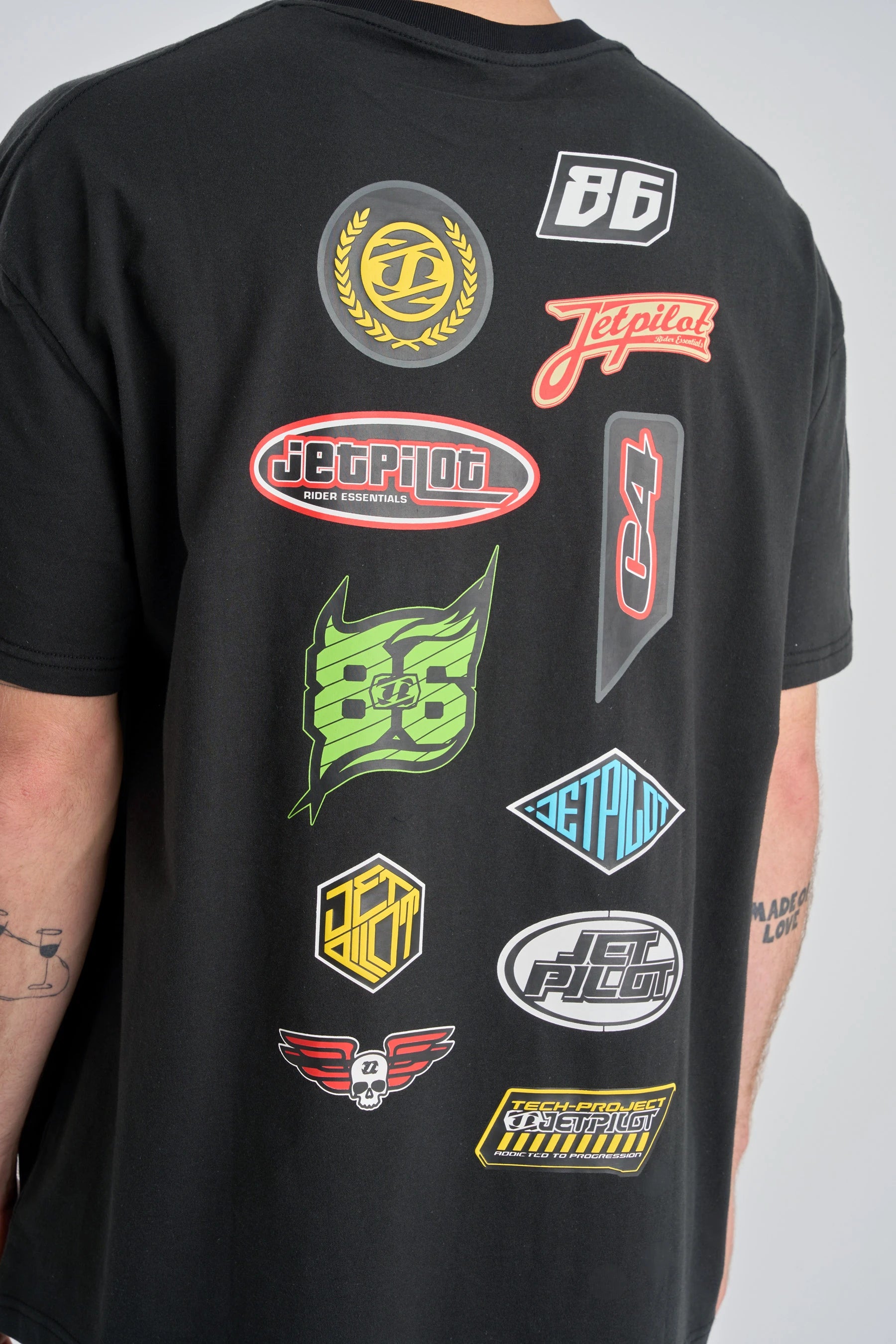 Jetpilot Factory Heavy Tee - Blackwith various colourful logos on a plain background — image 2