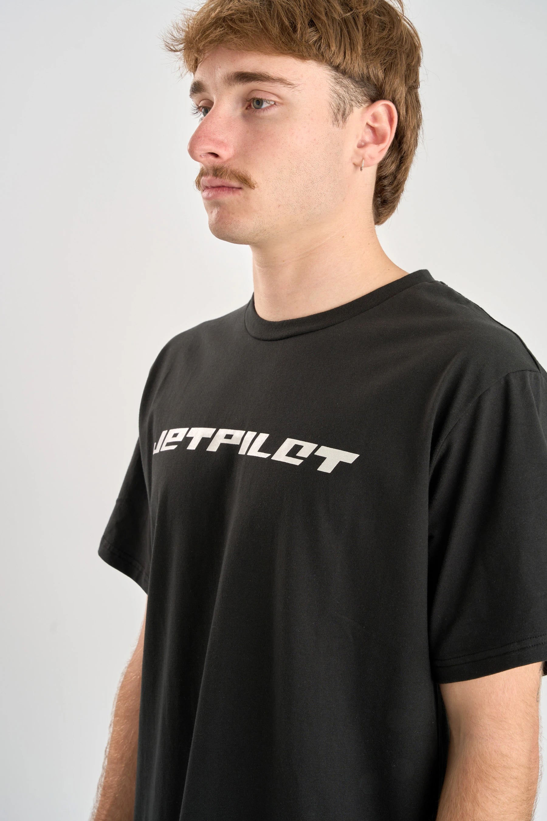 Man wearing a black t-shirt with 'Jetpilot' logo against a plain background — image 2