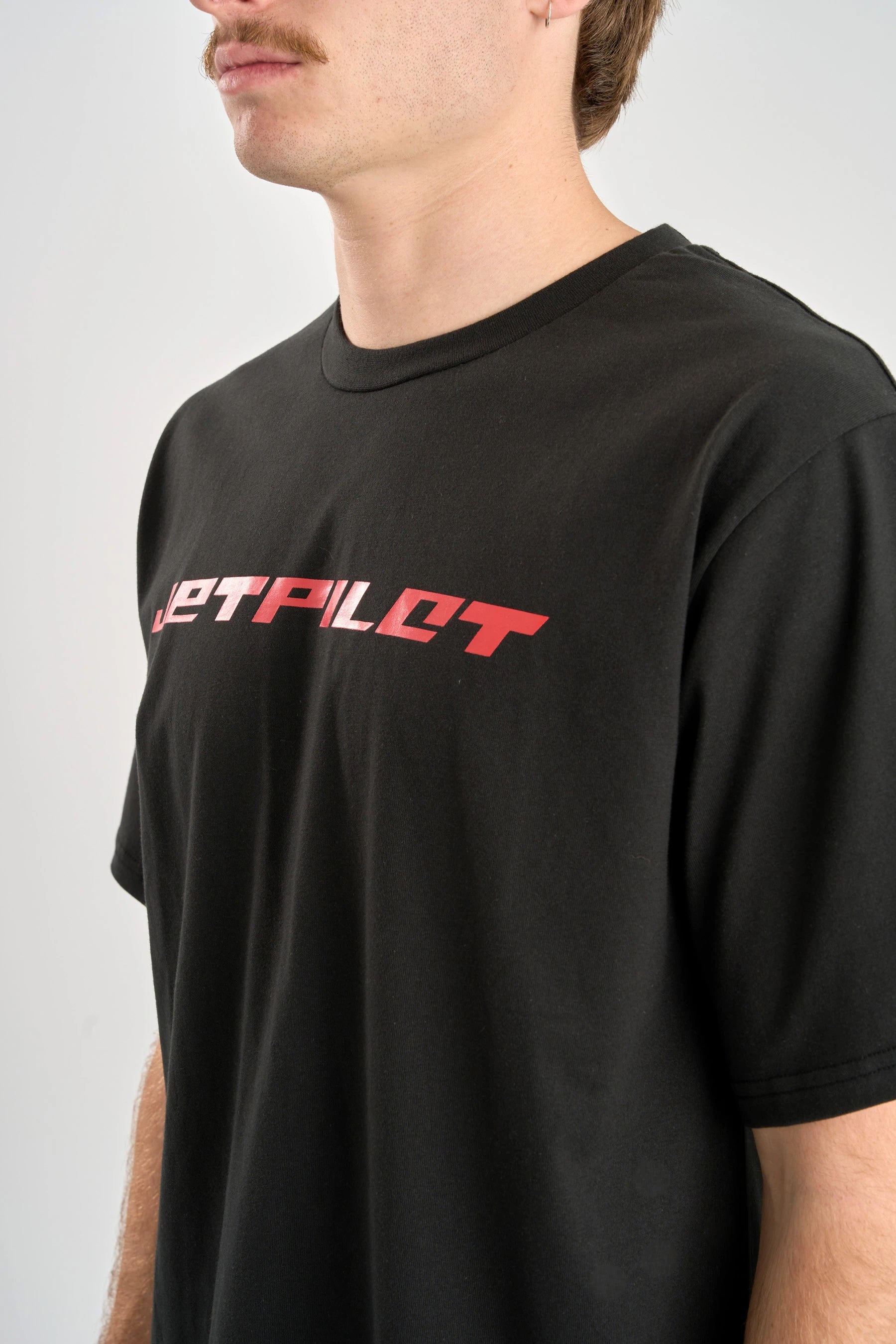 Person wearing a black t-shirt with red text on a plain background — image 2