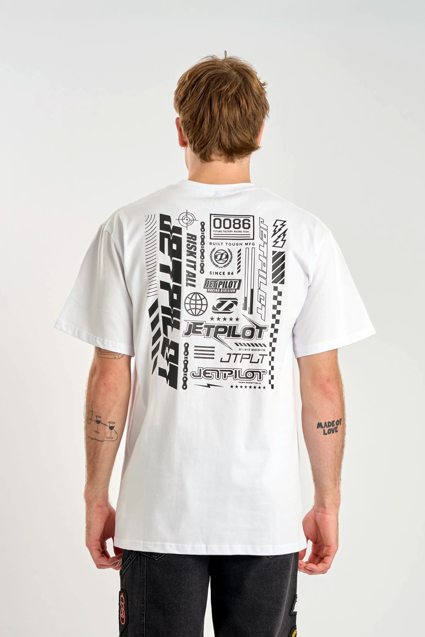 Person wearing a white t-shirt with Jetpilot logo brandings on the back against a plain background — image 2