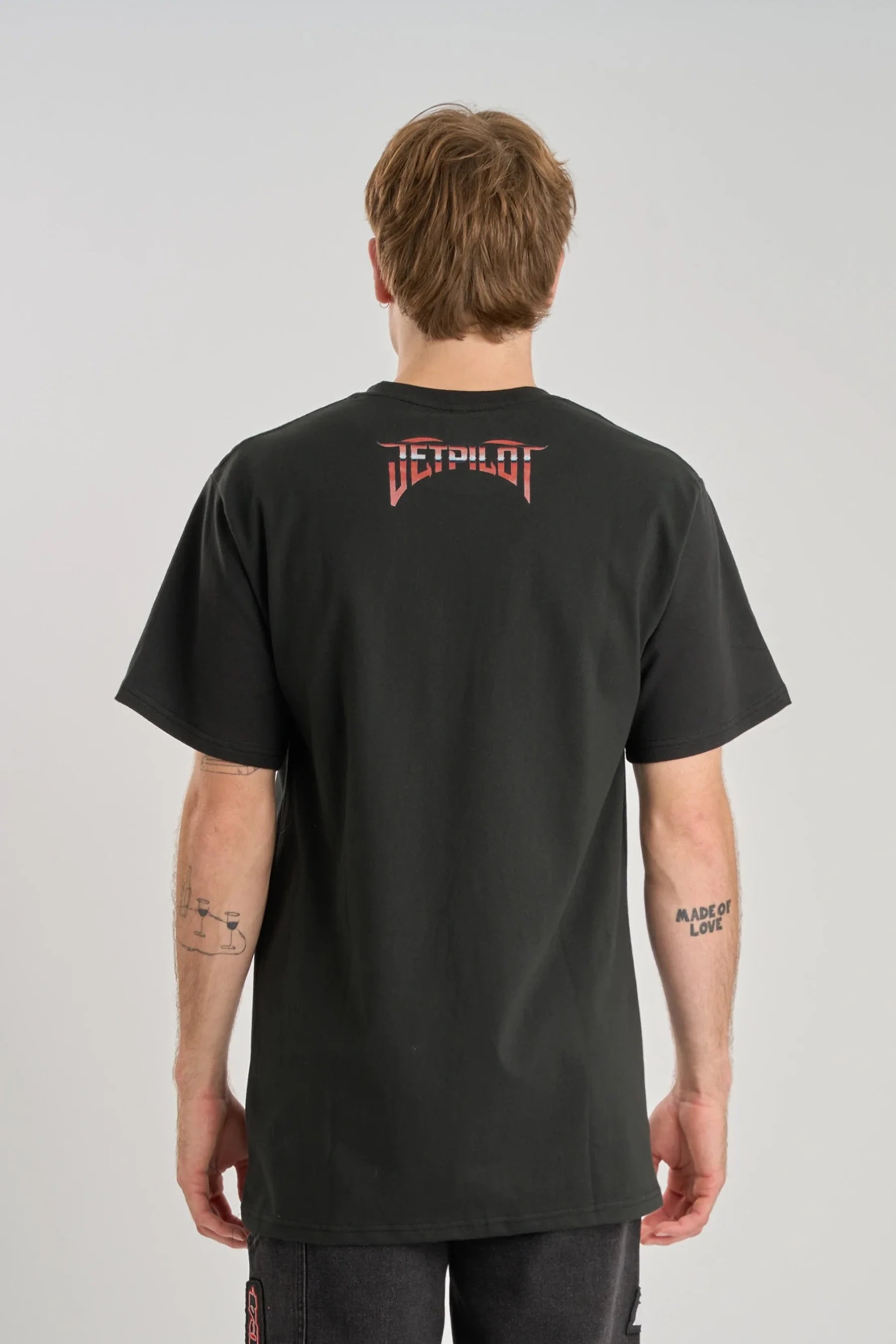 Person wearing a black t-shirt with a logo on the back against a gray background — image 2