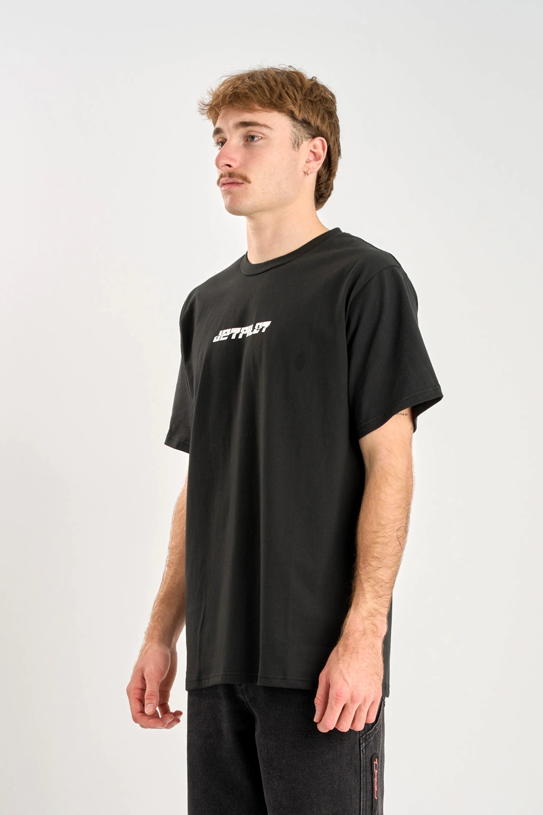 Person wearing a black Jetpilot Progressive t-shirt with white text on a white background — image 2