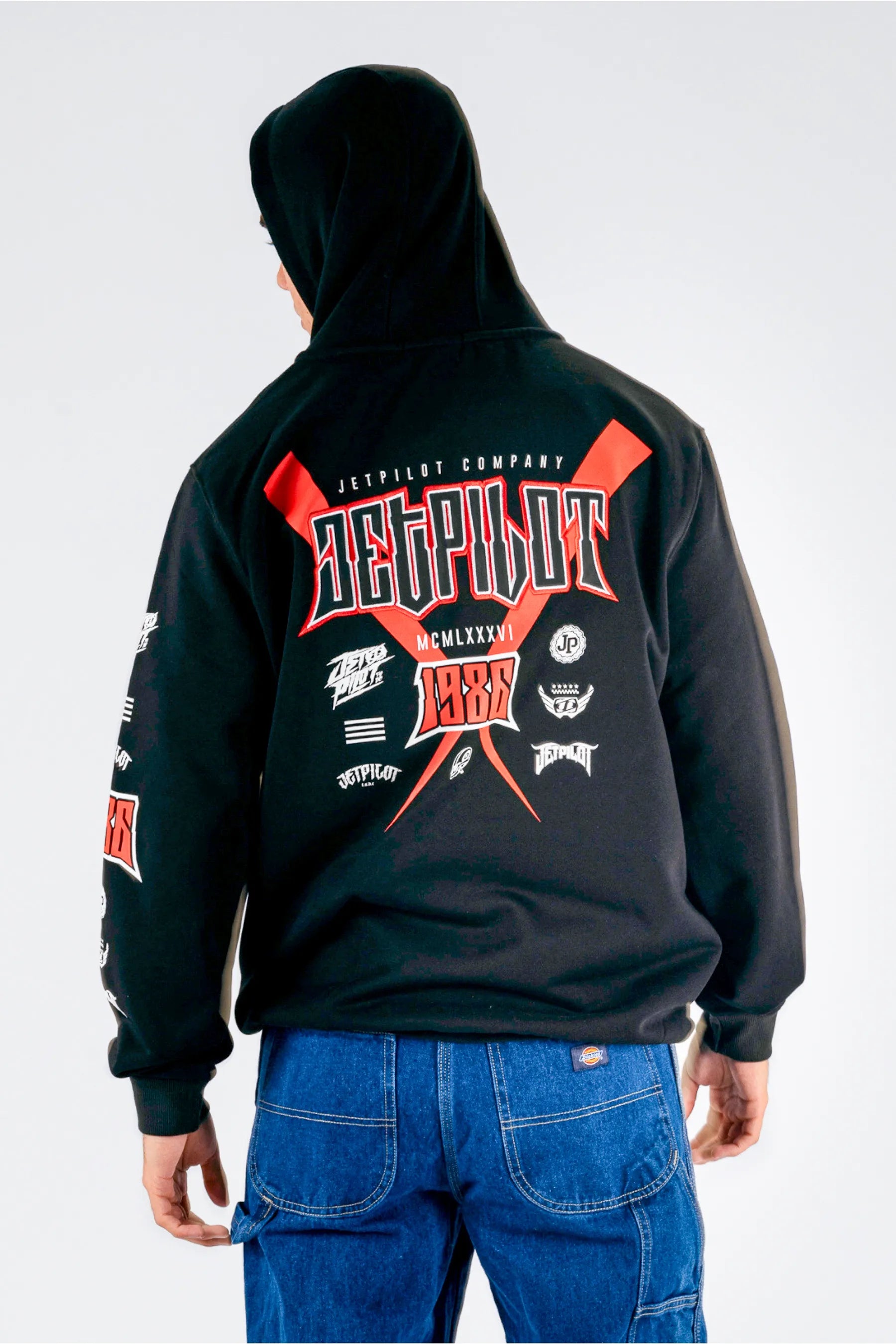 back view of a person wearing a black pullover with a Jetpilot logos on a white background — view 2 (5)