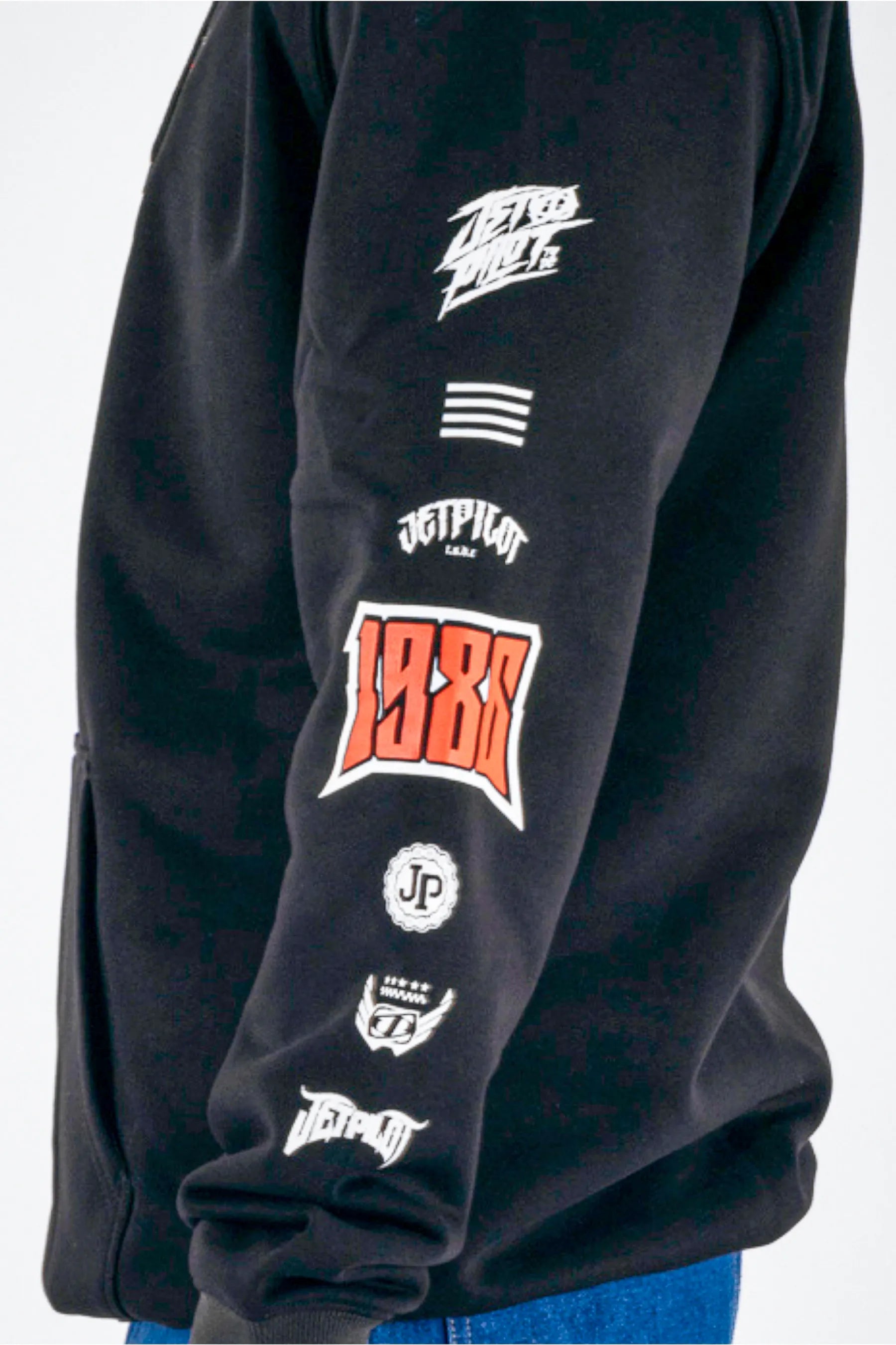 side view of a person wearing a black pullover with a Jetpilot logos on a white background — view 4 (3)