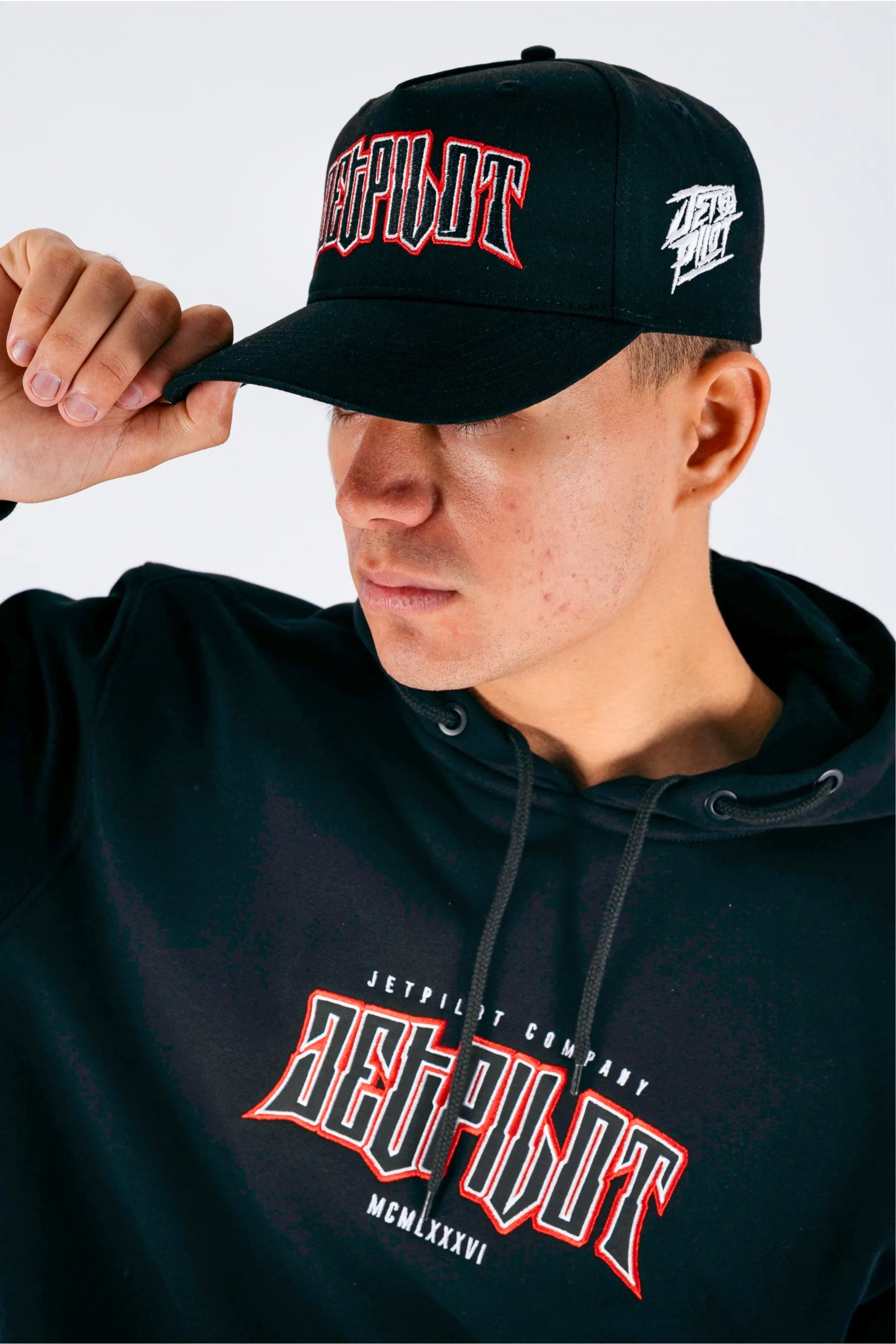 Left side view of a person wearing a black snapback with a Jetpilot logo on a white background — view 2 (3)
