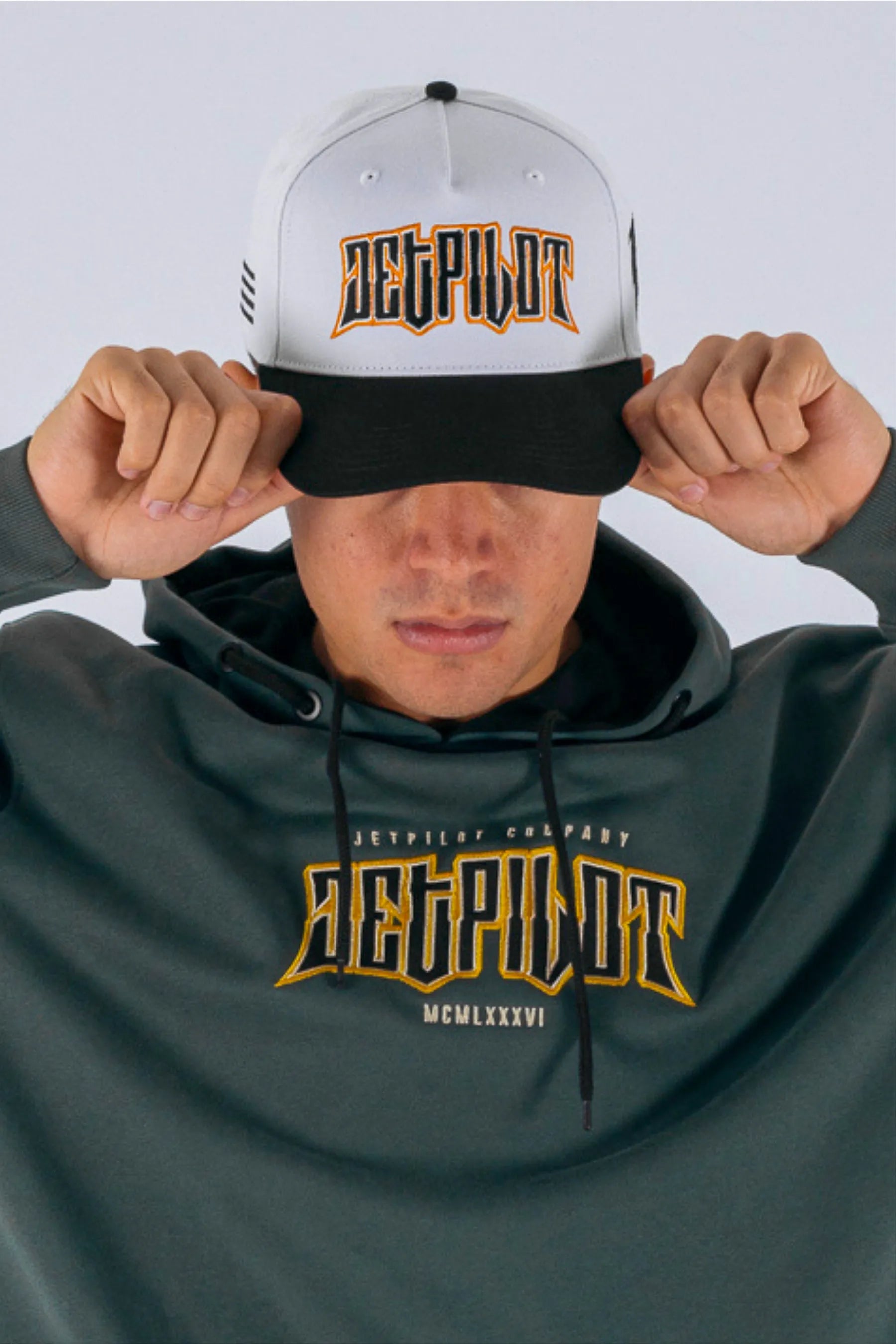 Close up of a person wearing a white snapback with a Jetpilot logo on a white background — view 3 (3)