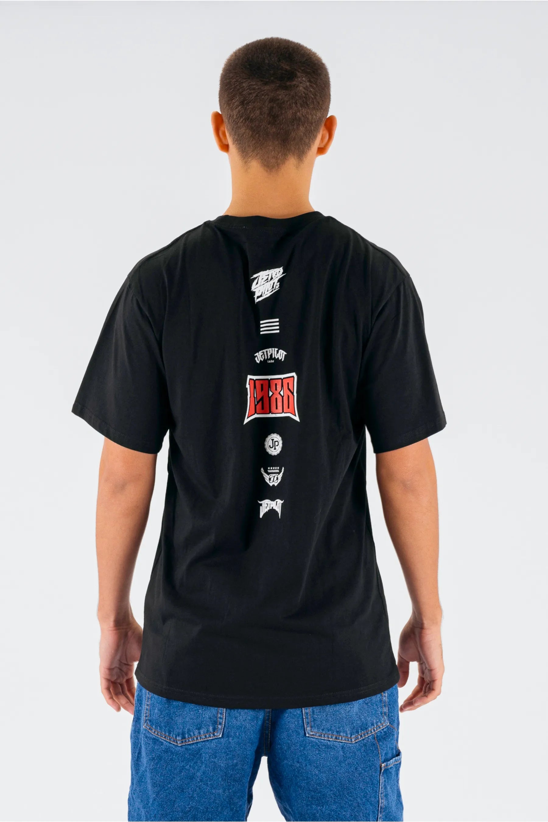 Person wearing a black t-shirt with designs on the back against a white background — view 2 (3)
