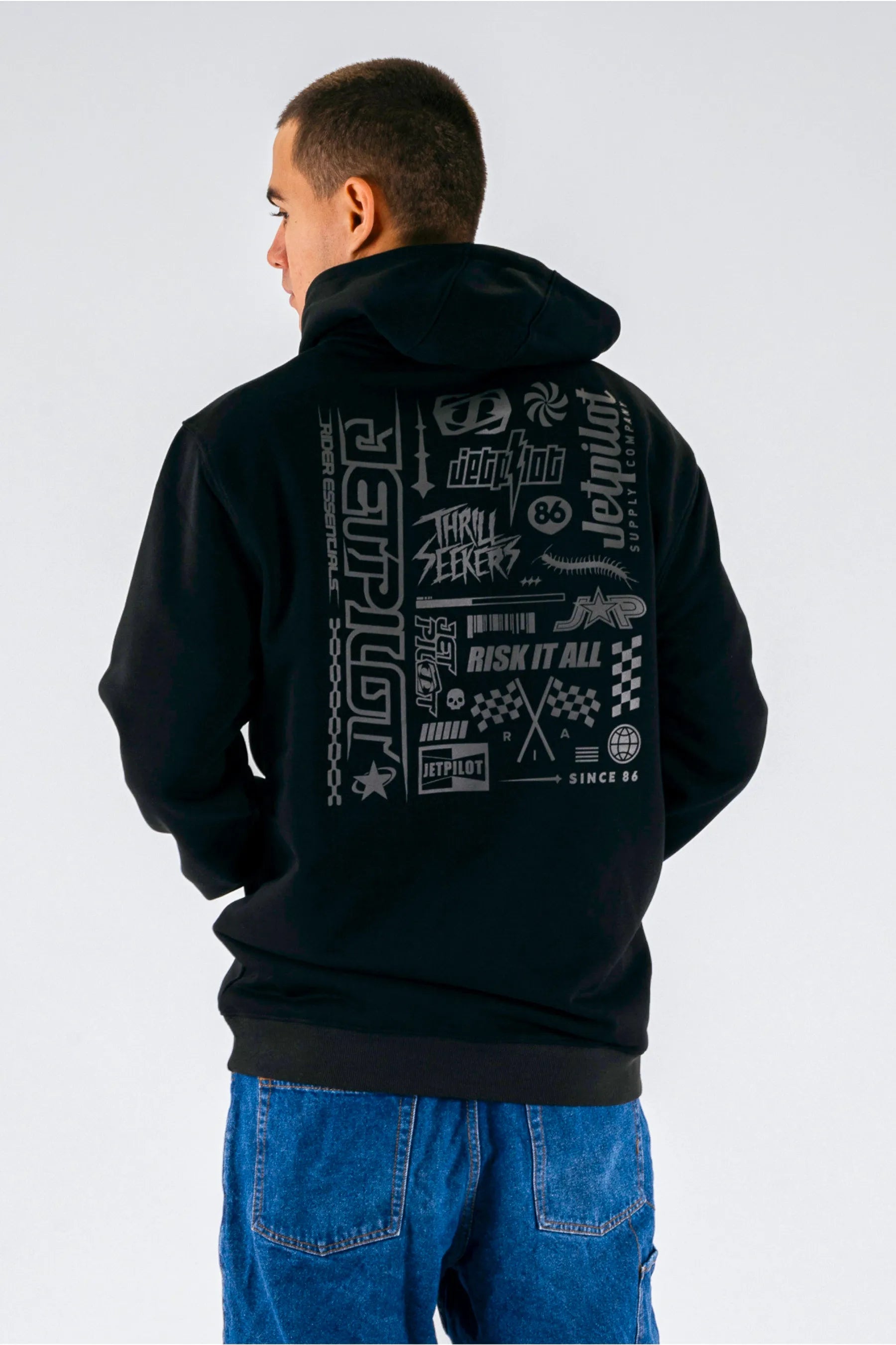 back view of a person wearing a black pullover with a Jetpilot logos on a white background — view 2 (6)