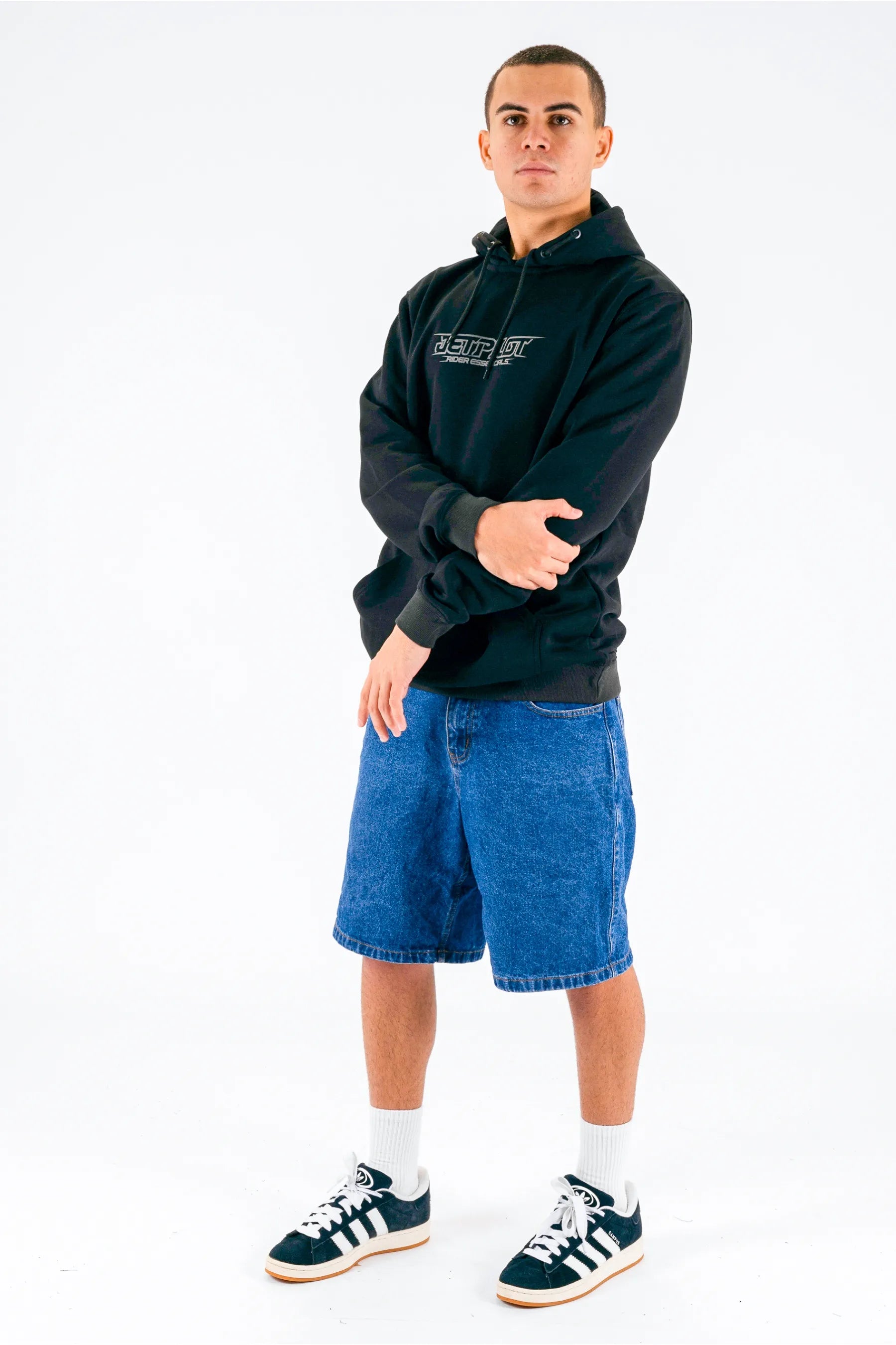 a person wearing a black pullover with a Jetpilot logo, blue shorts and a black/white shoes — view 5 (10)