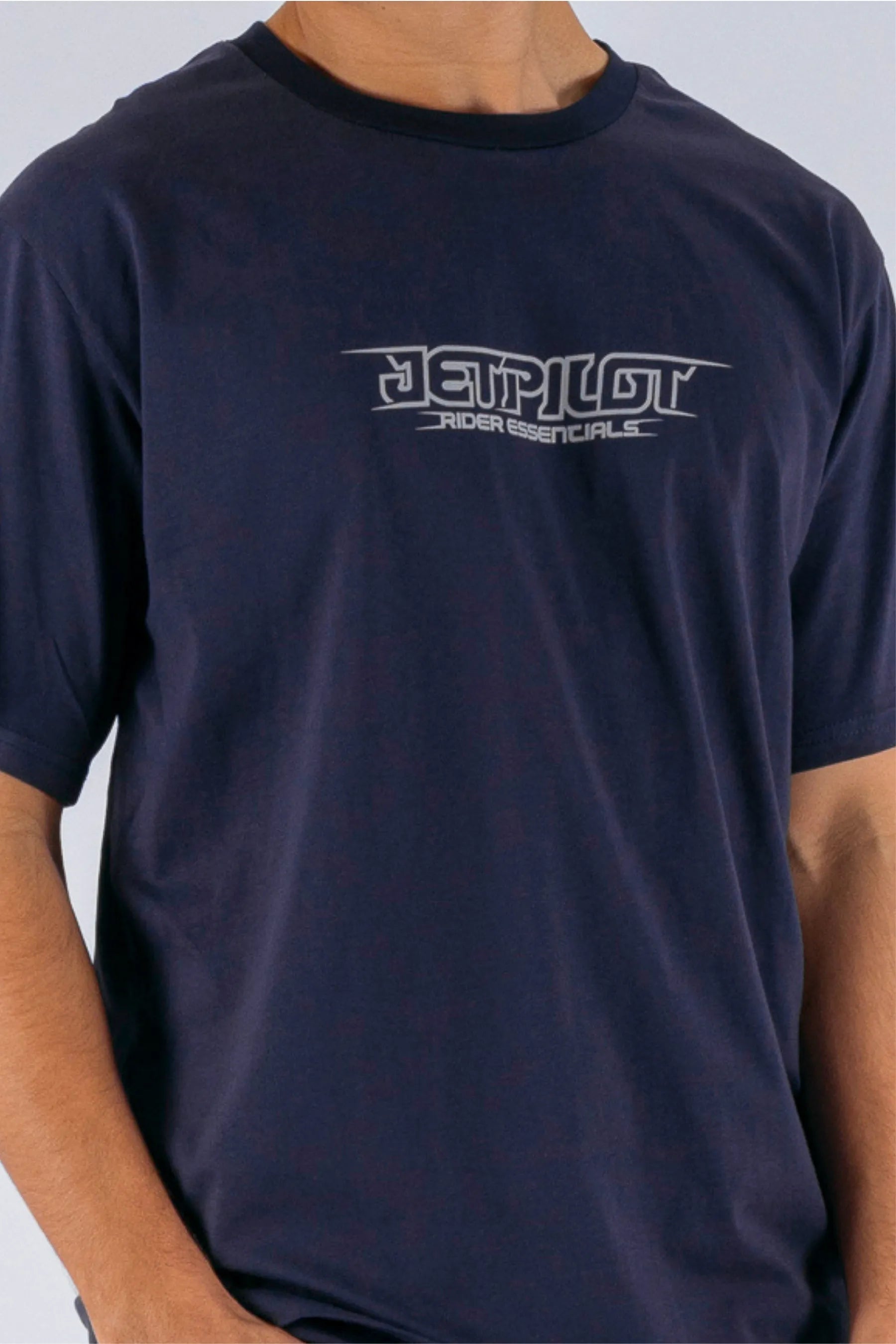 close up of a person wearing a dark blue tee with a Jetpilot logo on a white background — view 4 (4)