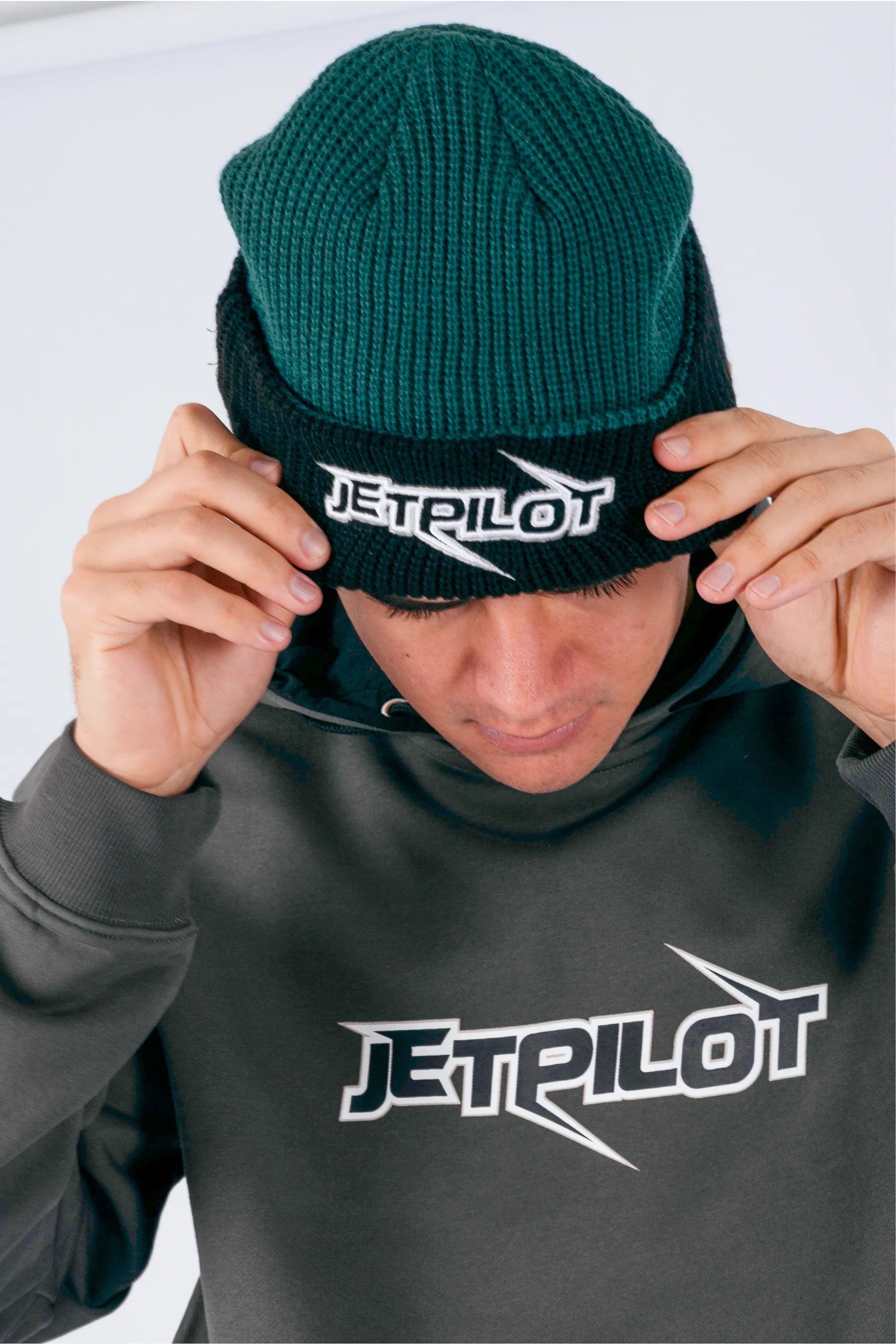 Close up of a person wearing a amazon green beanie with Jetpilot logo with a white background — view 3 (3)