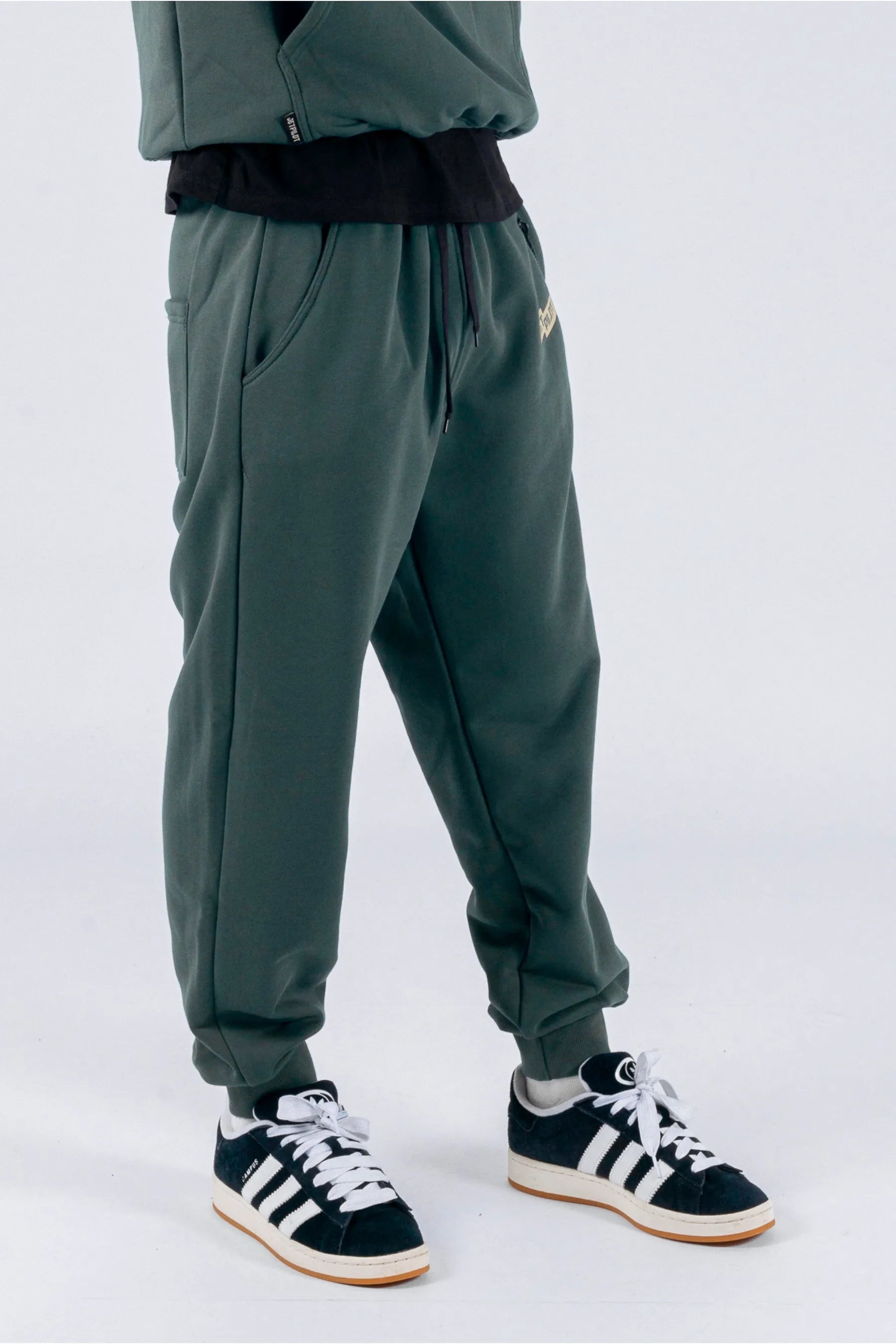 Right side view of a person wearing amazon green trackpants with a Jetpilot logo on a white background. — view 4 (3)
