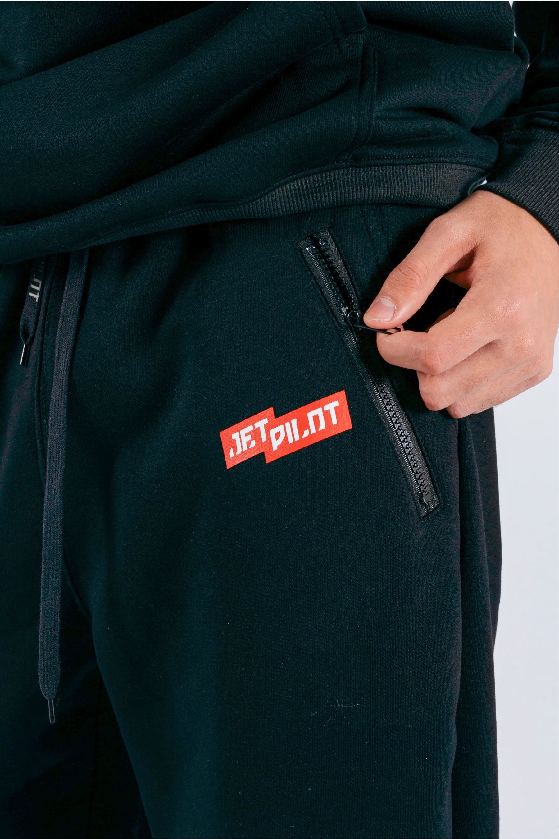 Close up of black trackpants red with red Jetpilot logo and zipper — view 4 (3)
