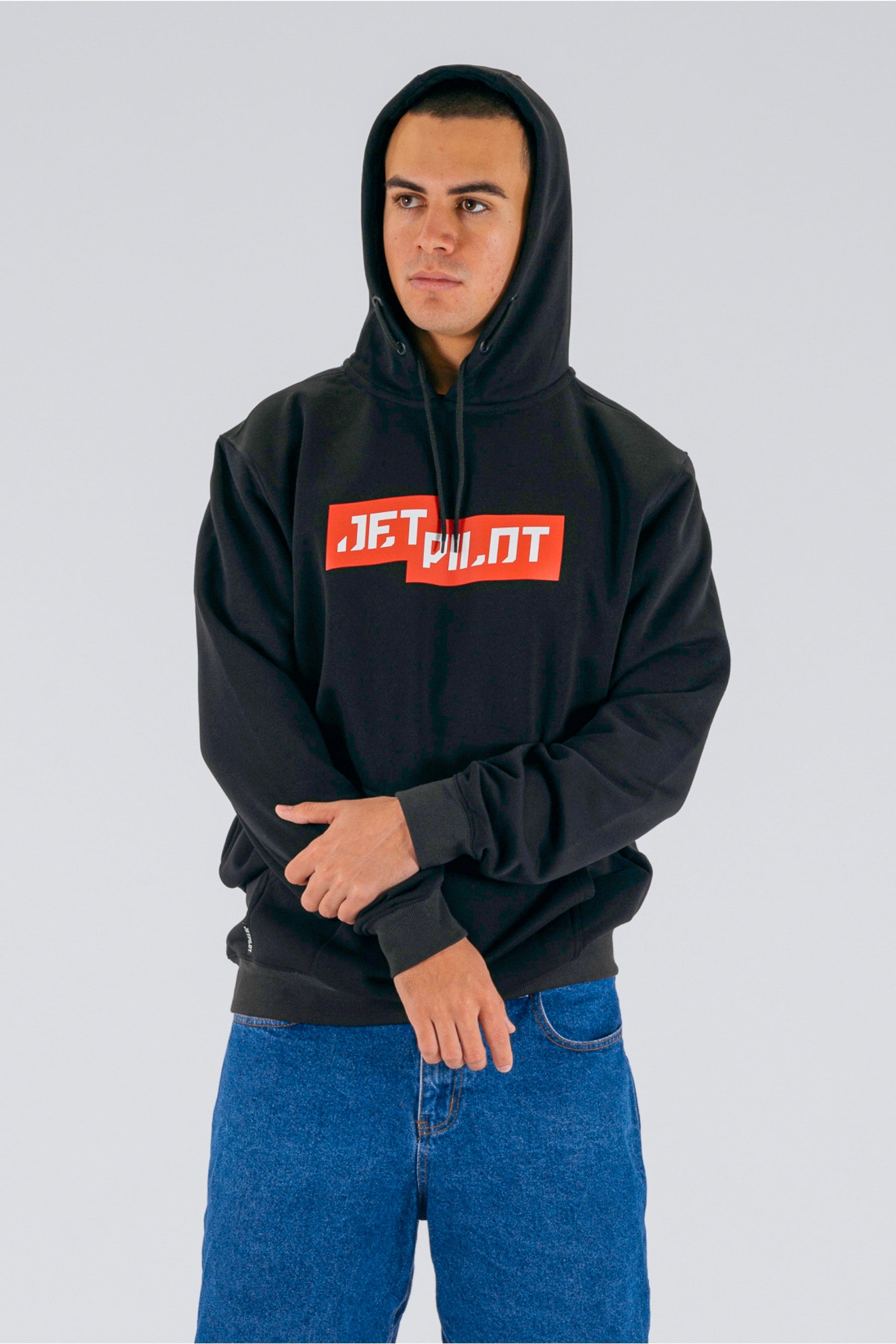 Front view of a person wearing the hood of a black pullover with a red on a white background Jetpilot logo — view 3 (3)