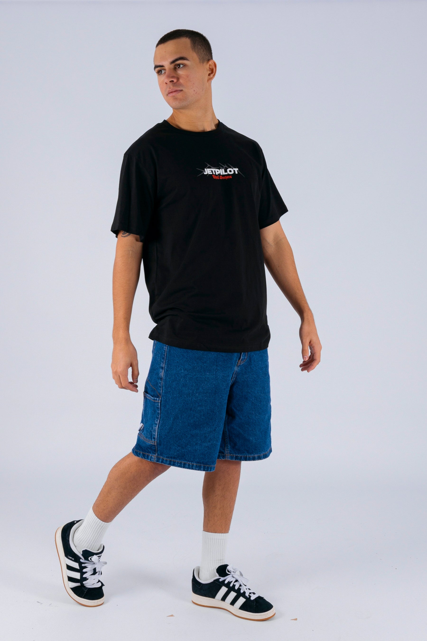 Front/side view of a person wearing a black tee with a white Jetpilot logo on a white background — view 3 (3)