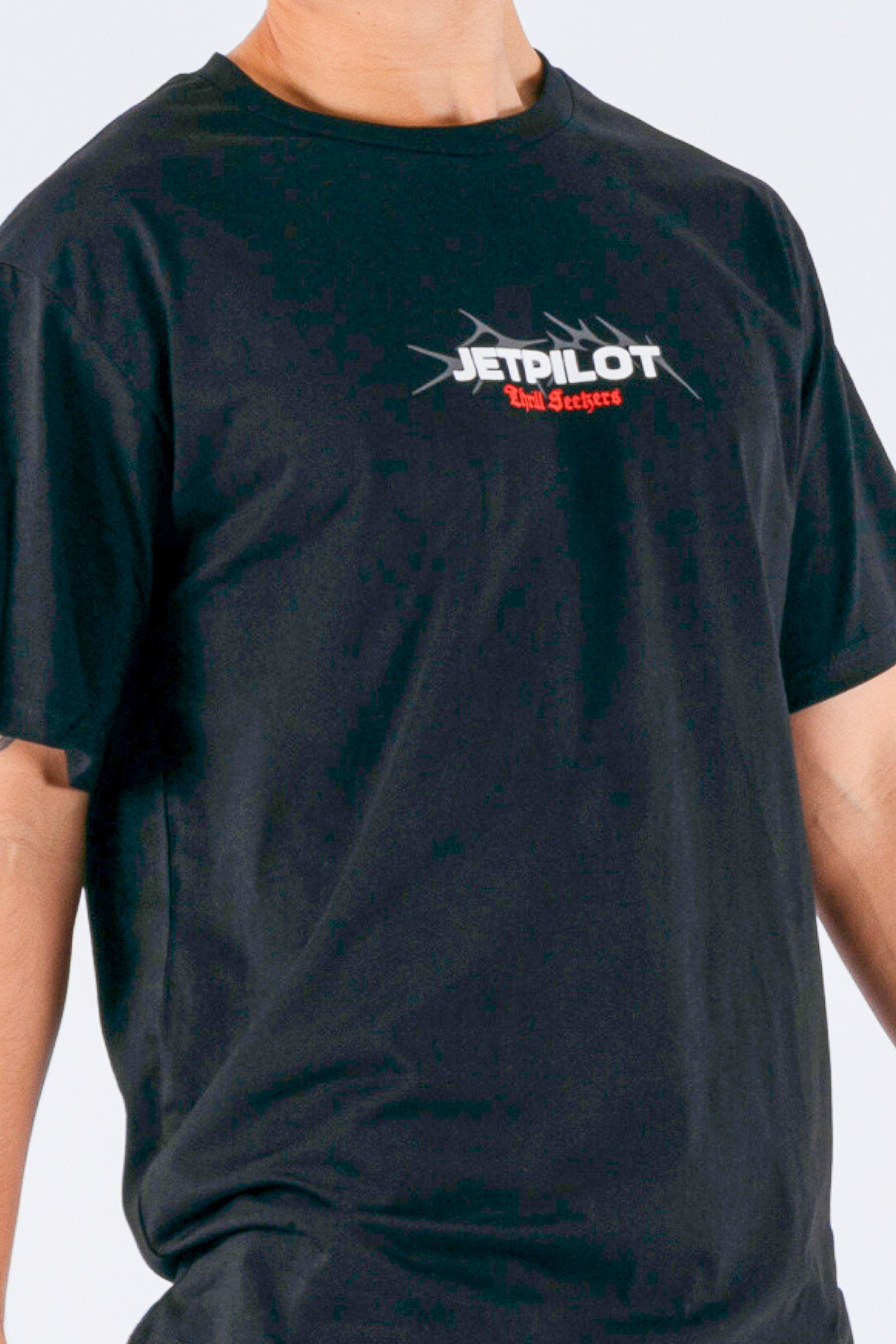 Close up of a person wearing a black tee with a white Jetpilot logo on a white background — view 5 (3)