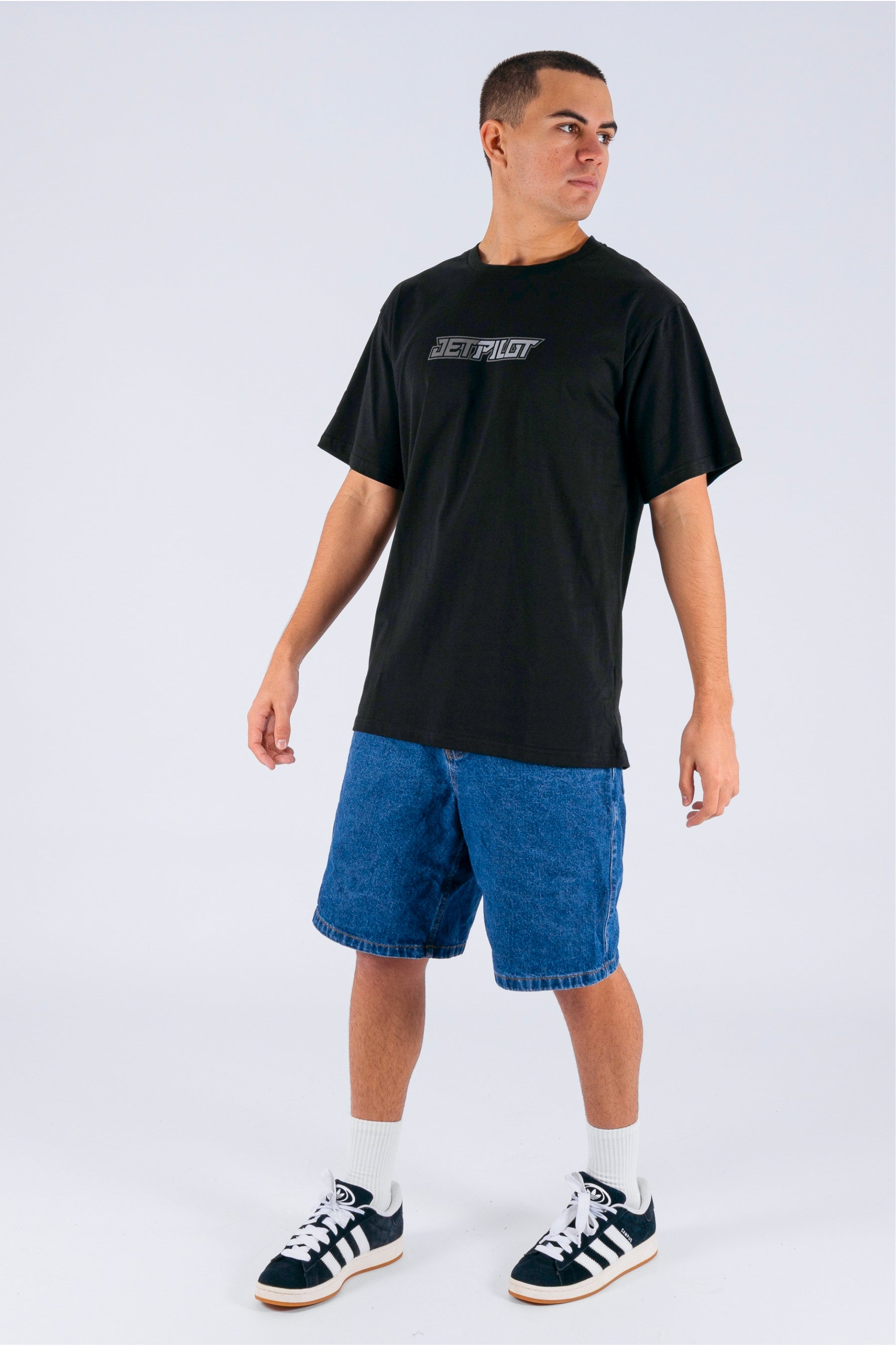 a person wearing a black tee, blue pants and white/black shoes on a white background — view 3 (3)