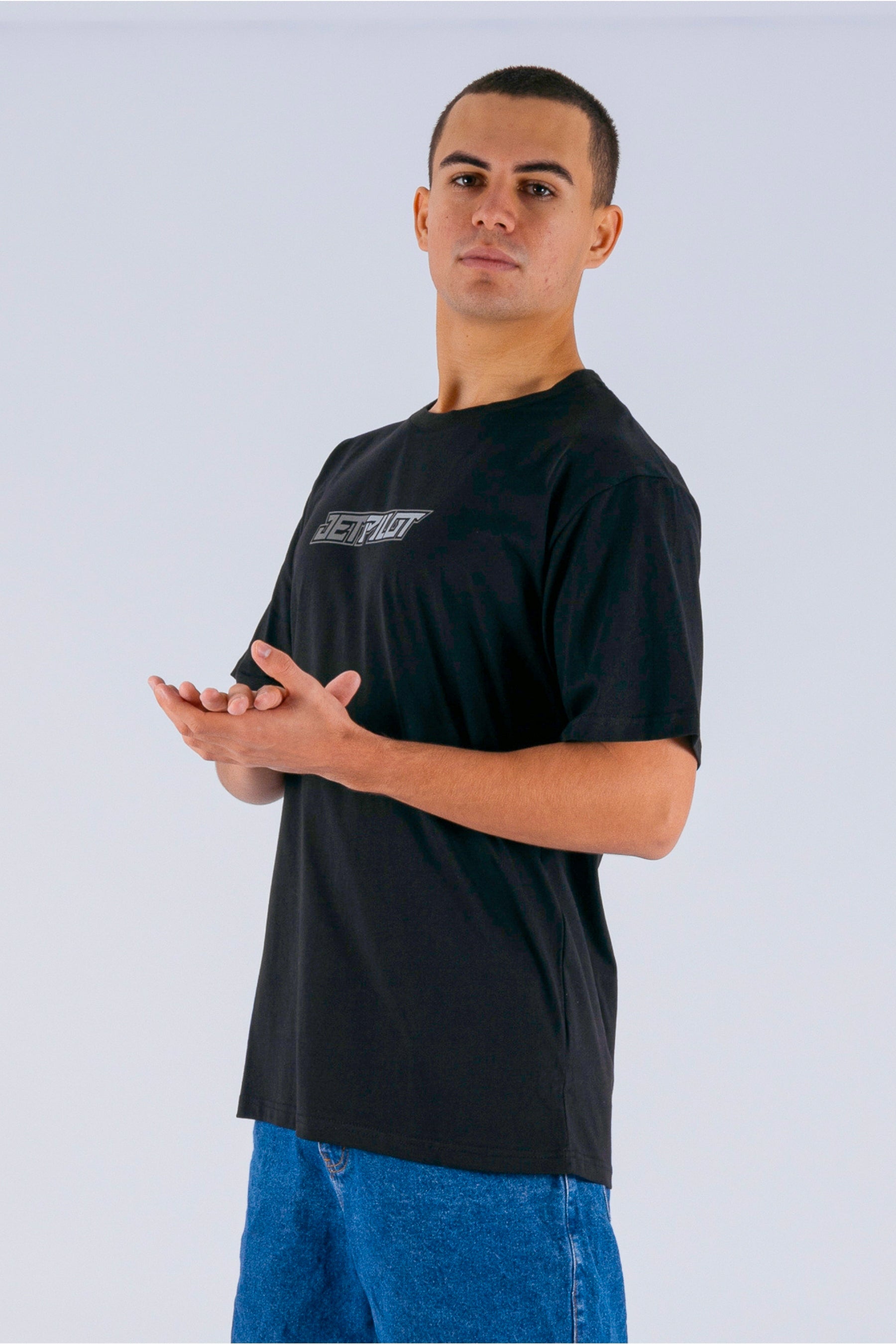 side view of a person wearing a black tee with a Jetpilot logo on a white background — view 5 (3)