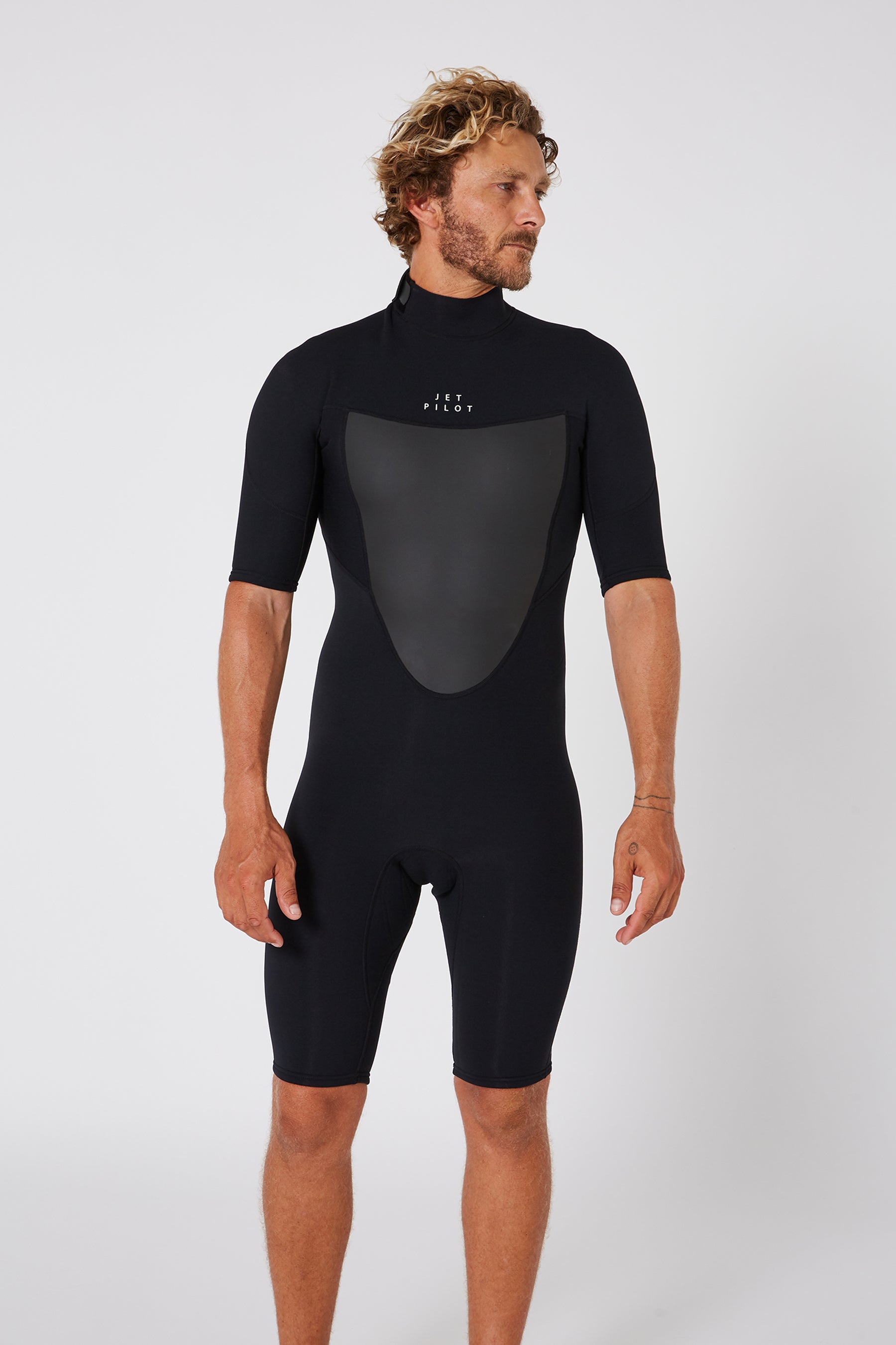 A man wearing a black short sleeve Jetpilot Flight springsuit with a back zip, designed for watersports.