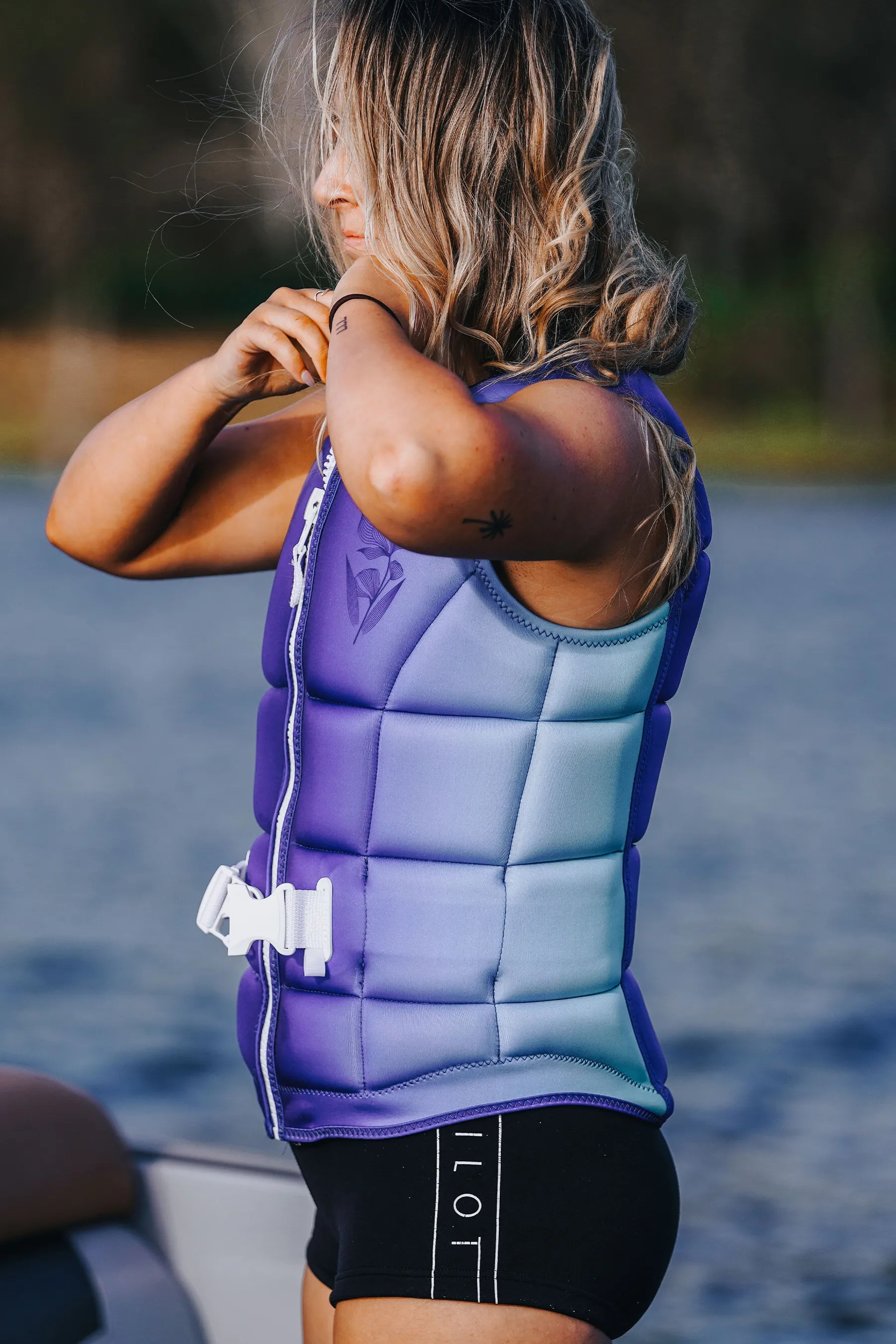 Person wearing aJetpilot Aurora Ladies Life Jacket - Blue life vest on a body of water.